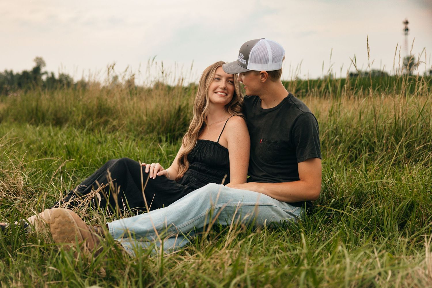 Couple relaxing together in a grassy meadow on a warm summer day.
