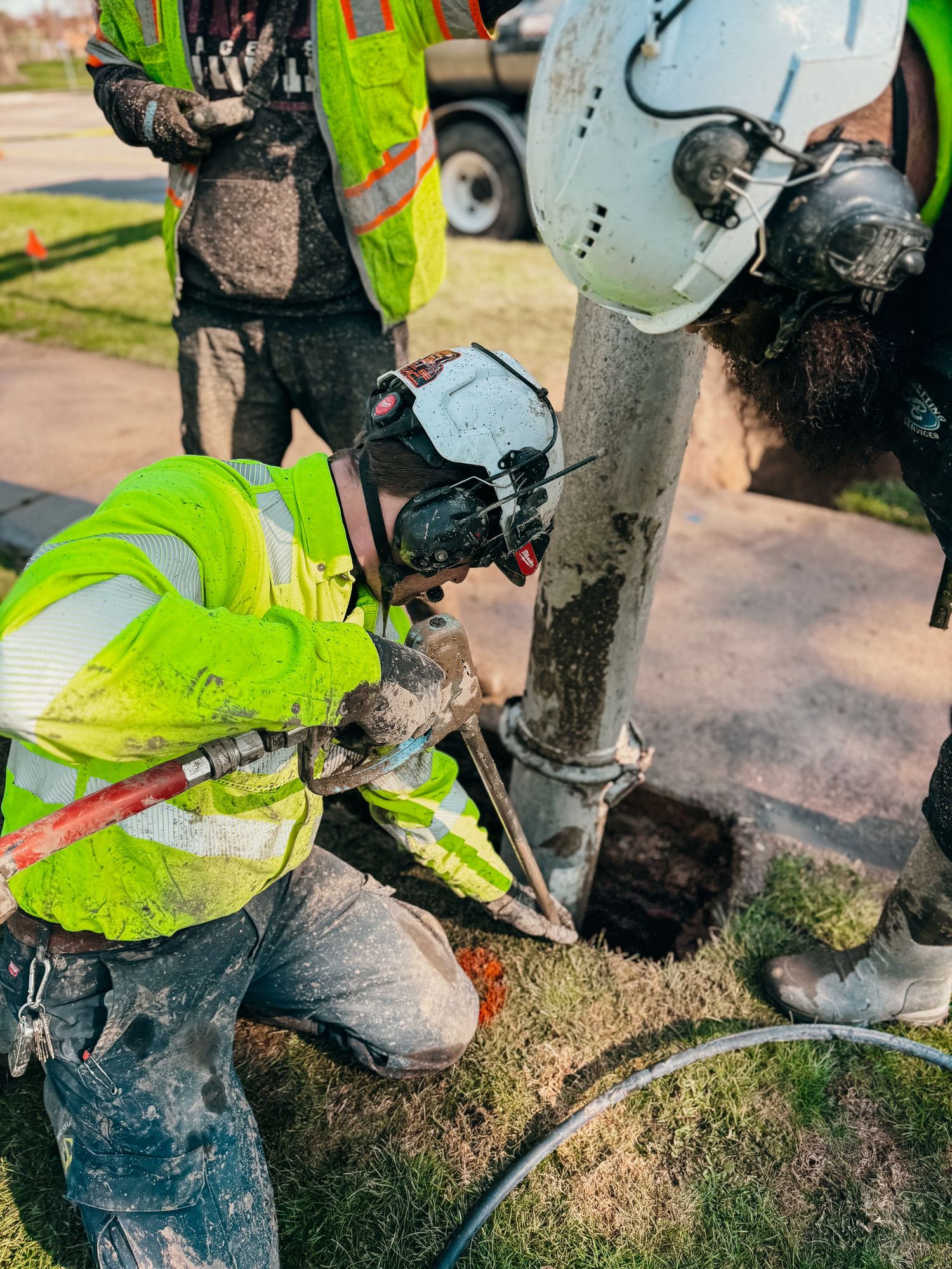 Worker in safety gear using specialized equipment to repair underground utilities.