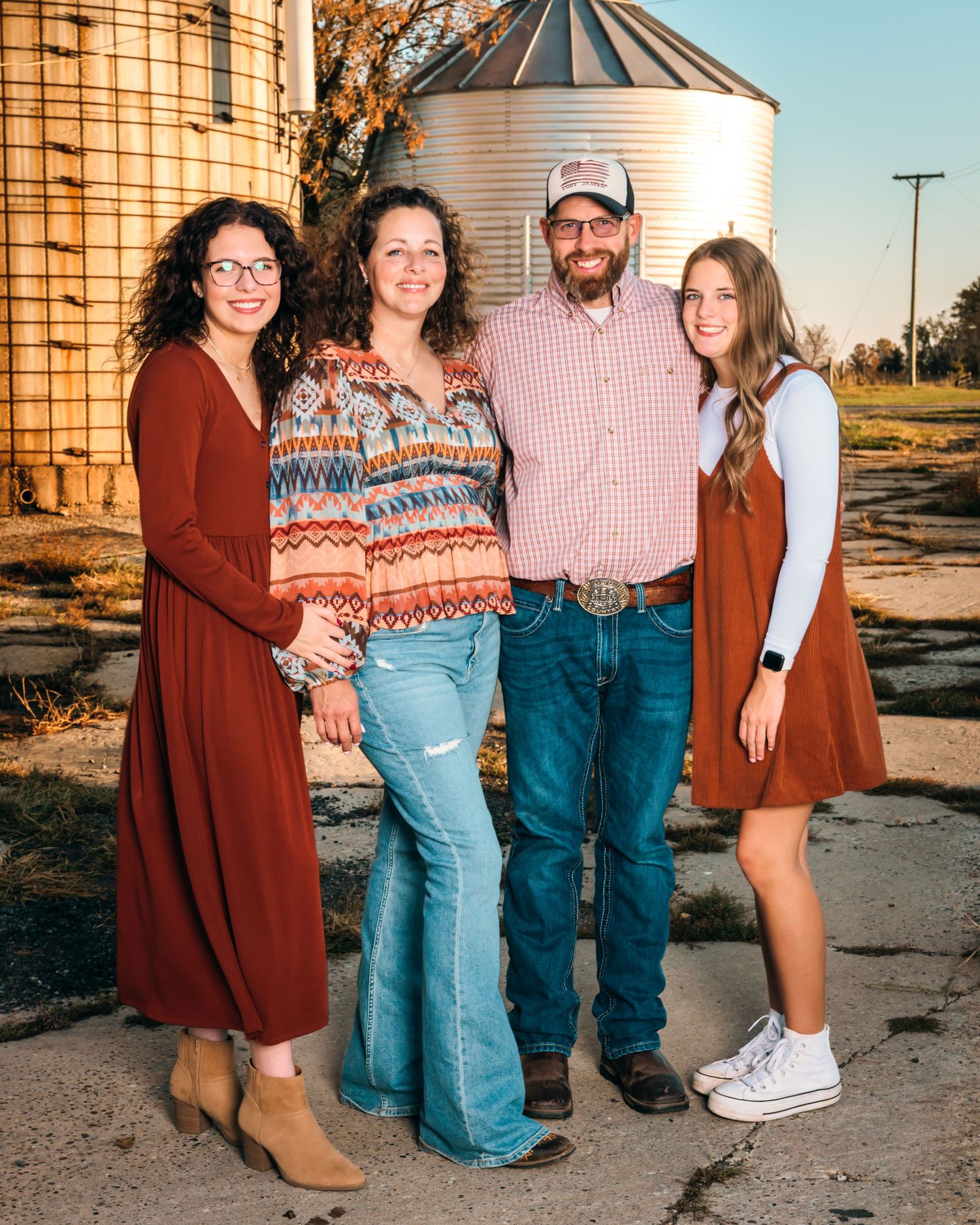 Family portrait session in front of rustic grain silos at sunset.