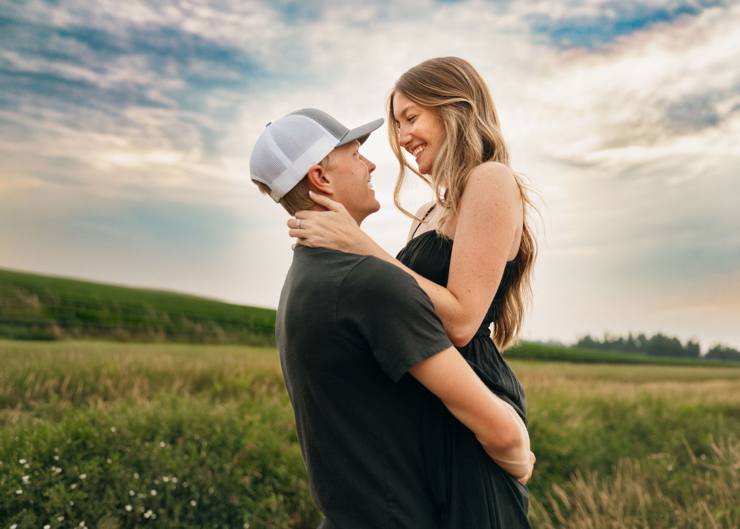 Couple embracing in a sunny wildflower field during golden hour.