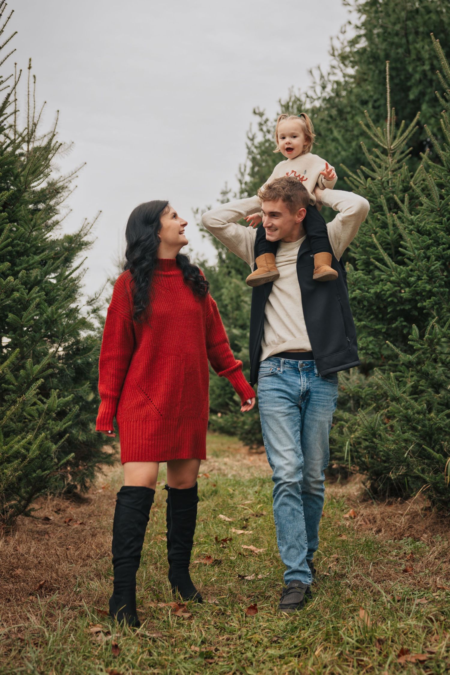 Family enjoying time together at a Christmas tree farm on a cloudy day.