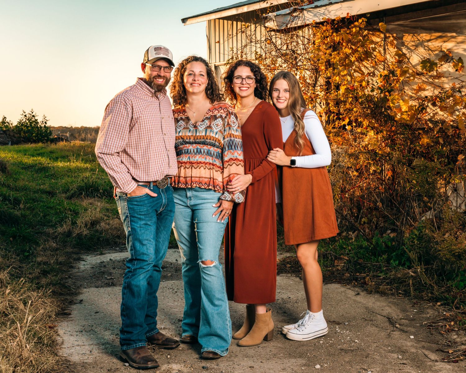 A family group stands together on a dirt path during golden hour.