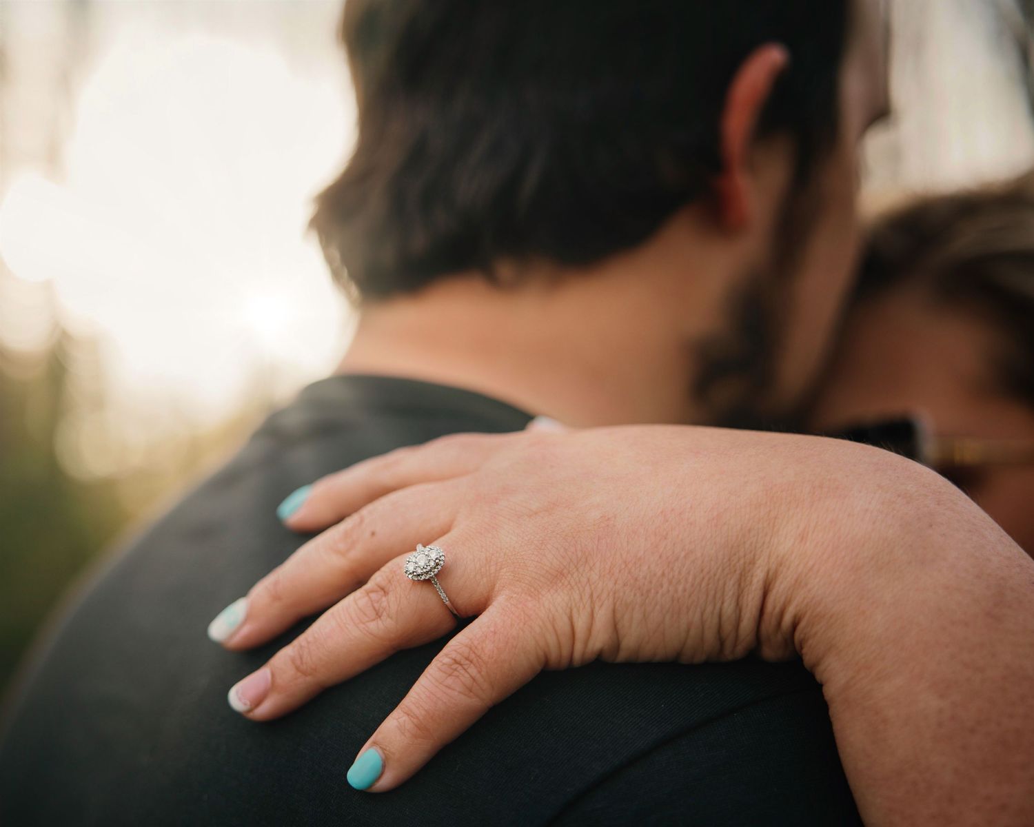 Close-up shot of hands gently resting on shoulders showing intimacy.