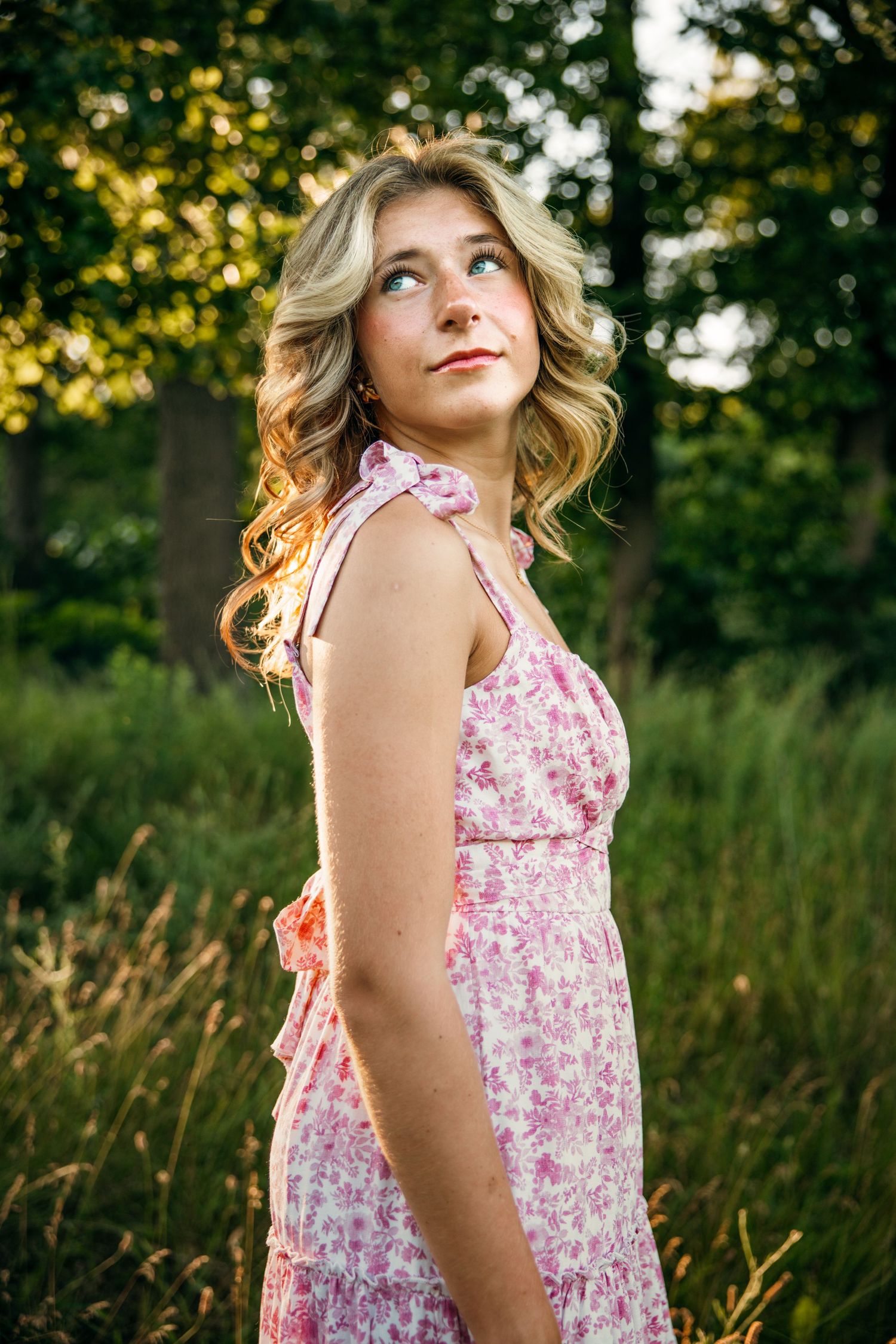 A flowing pink floral dress catches sunlight in a golden hour outdoor portrait.