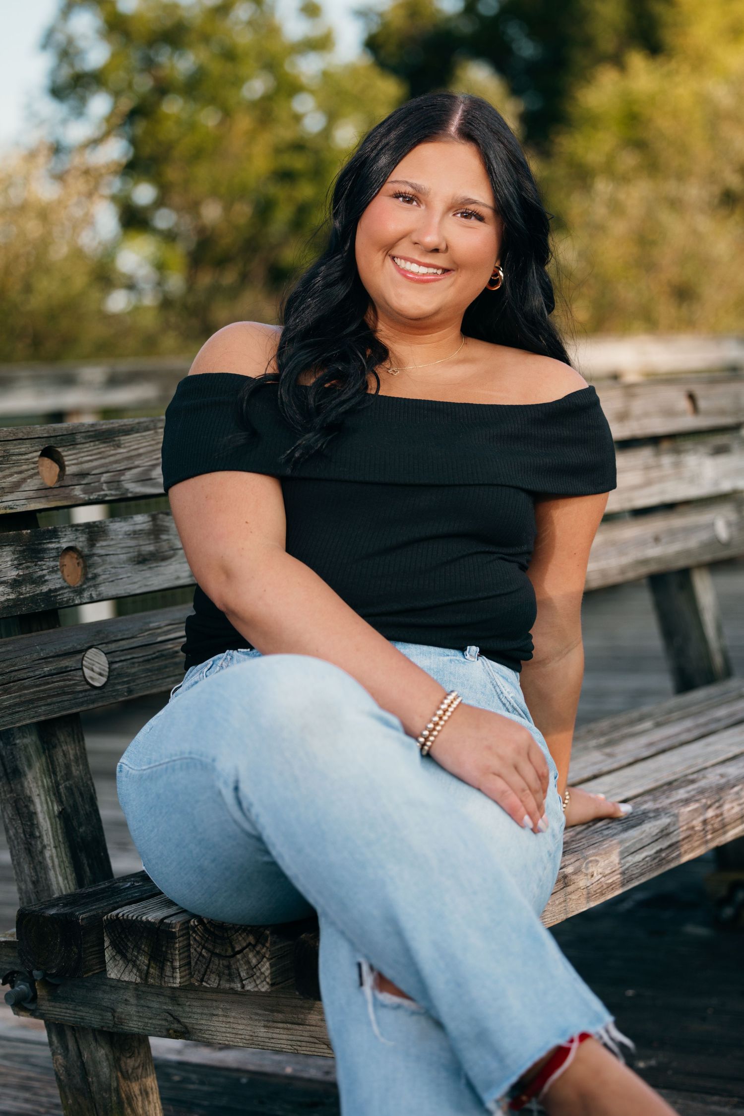Portrait session on wooden deck wearing black top and light denim jeans.