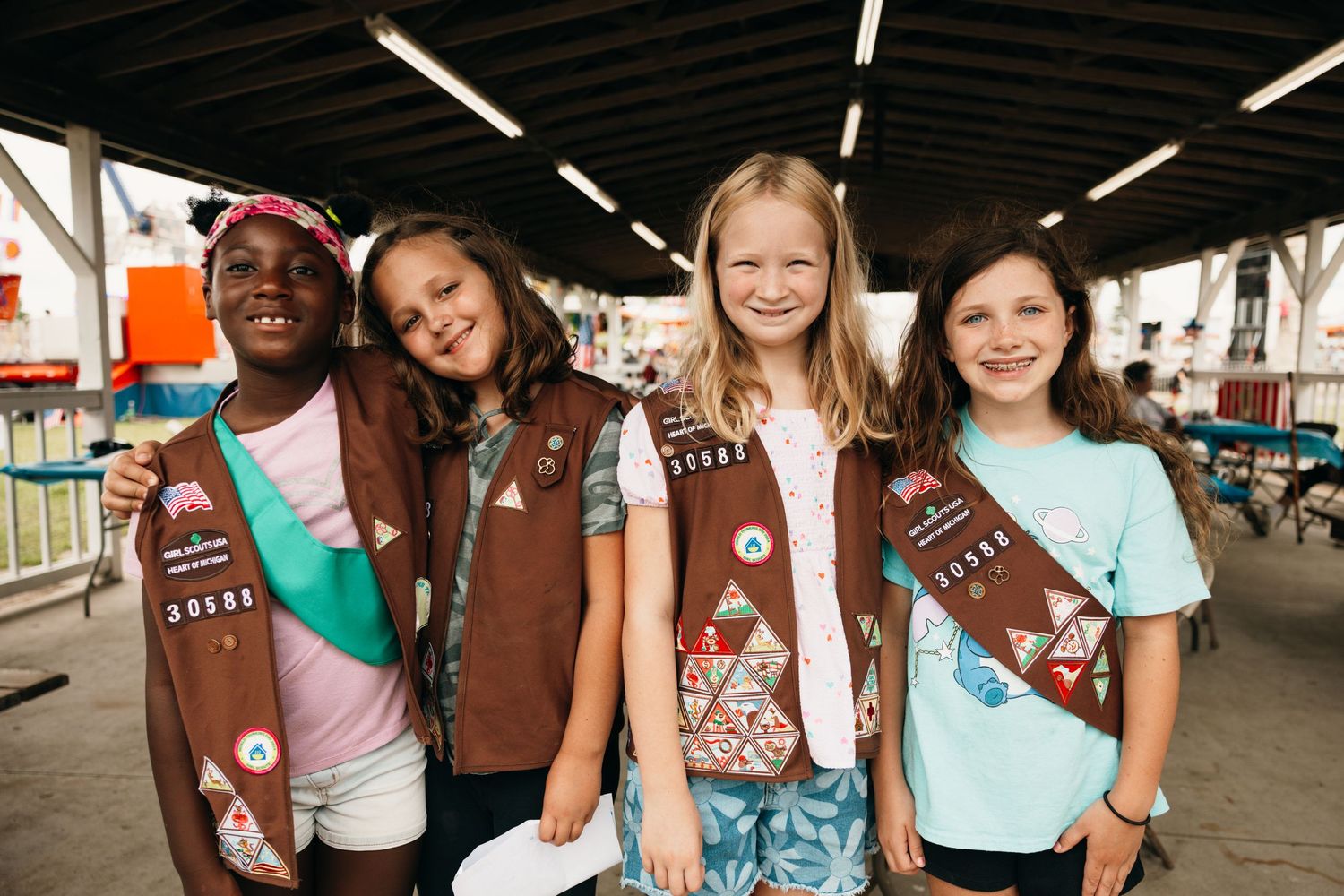 Group of Girl Scouts in brown uniforms gathered at a community event.
