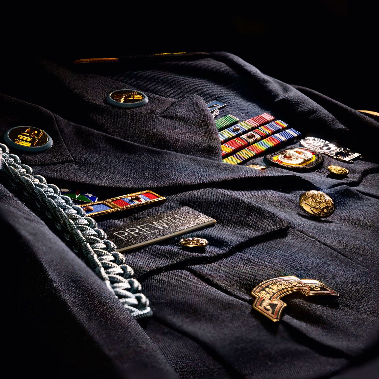 Close-up of military or service uniform with pins and badges on dark fabric.