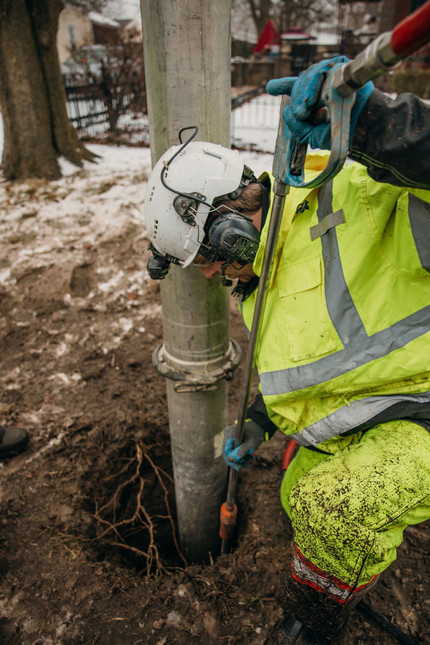 Worker in high-visibility safety gear performing underground utility work.