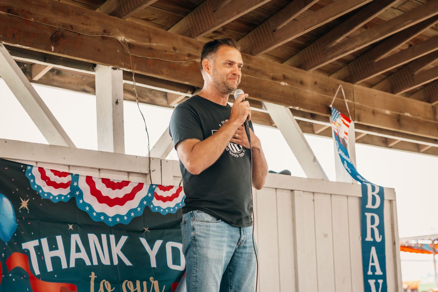 Rustic wooden venue decorated with patriotic bunting and thank you signs for an event.