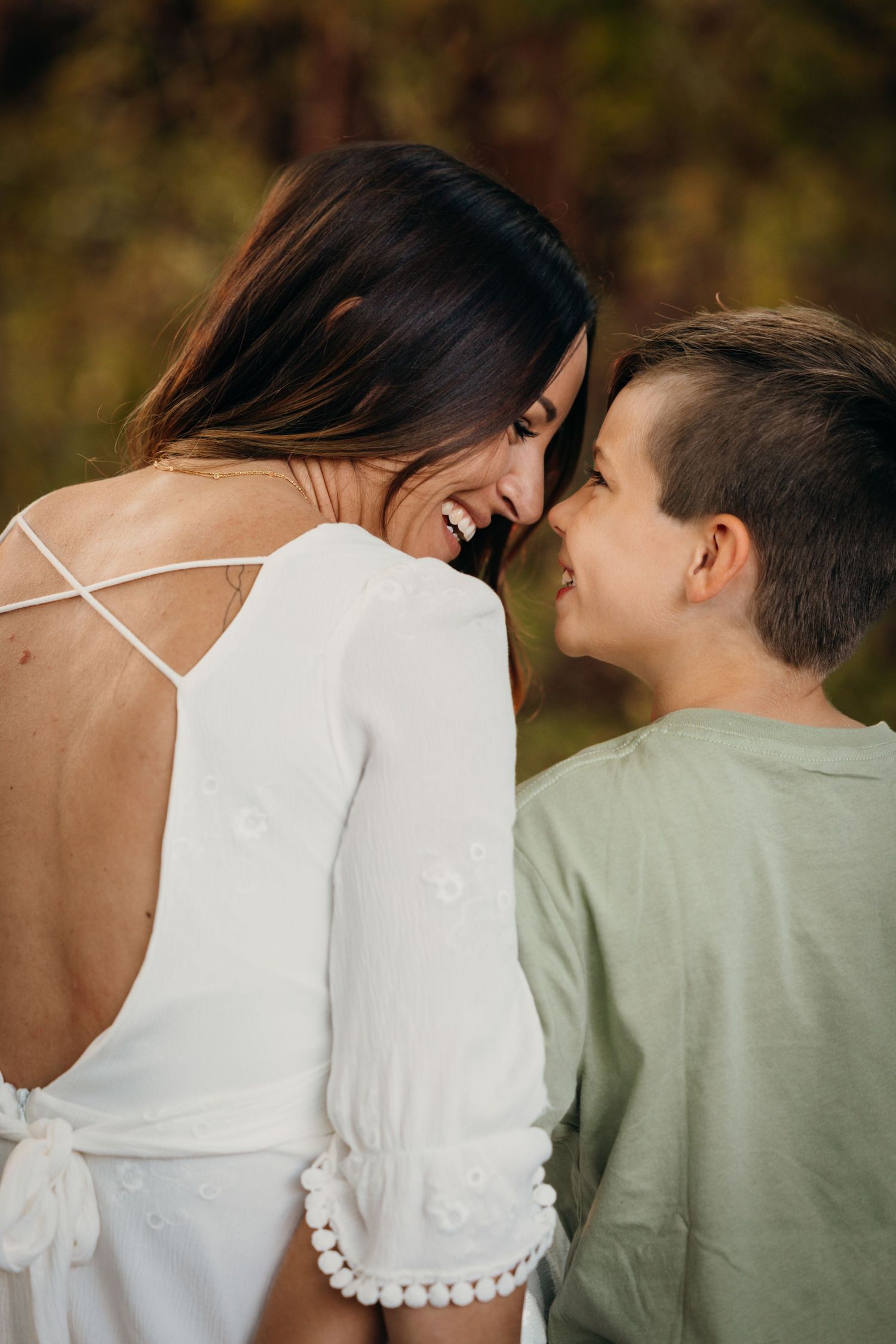 Two people sharing an intimate laughing moment outdoors in warm sunlight.