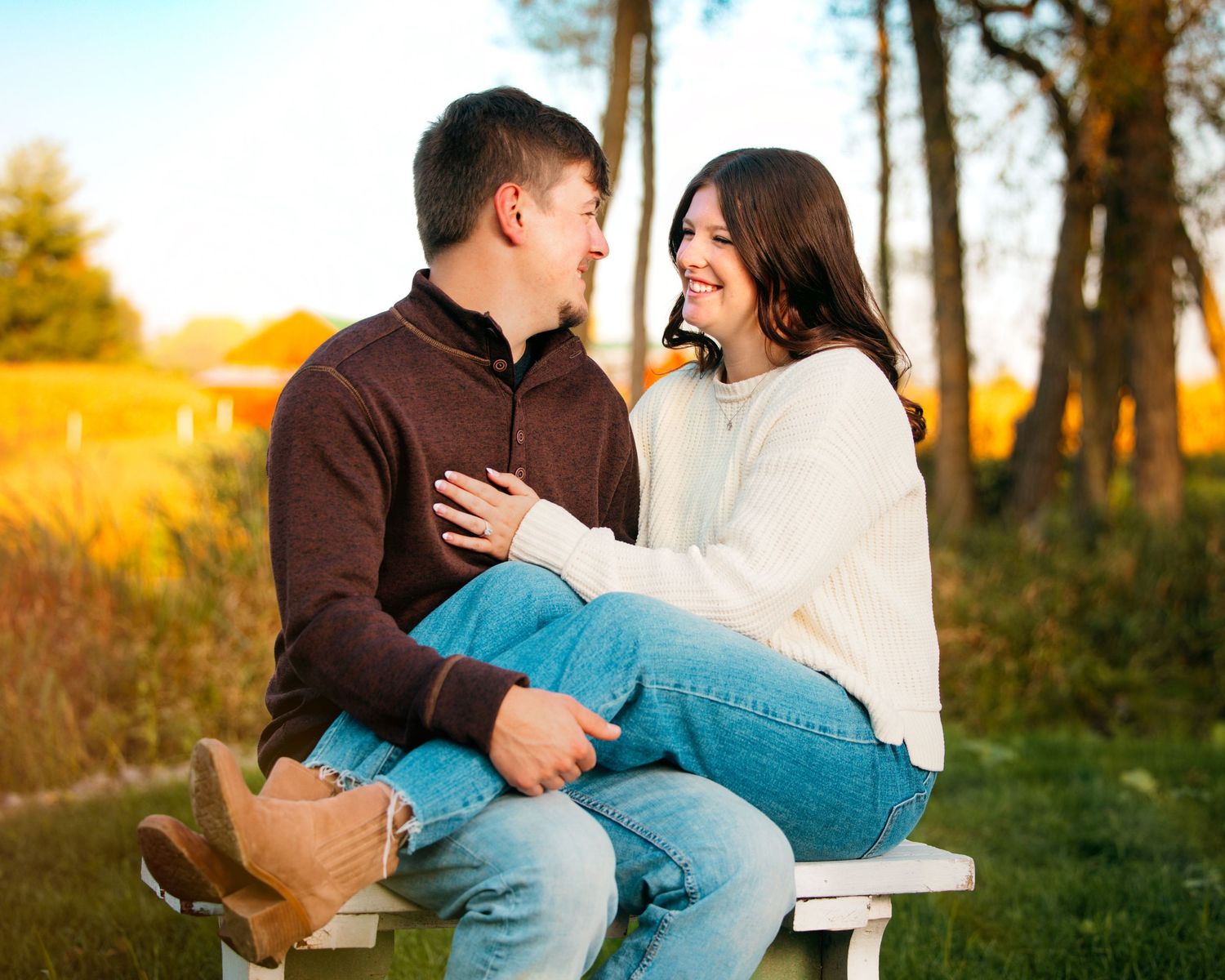 Romantic couple embraces playfully in a golden autumn field during sunset.