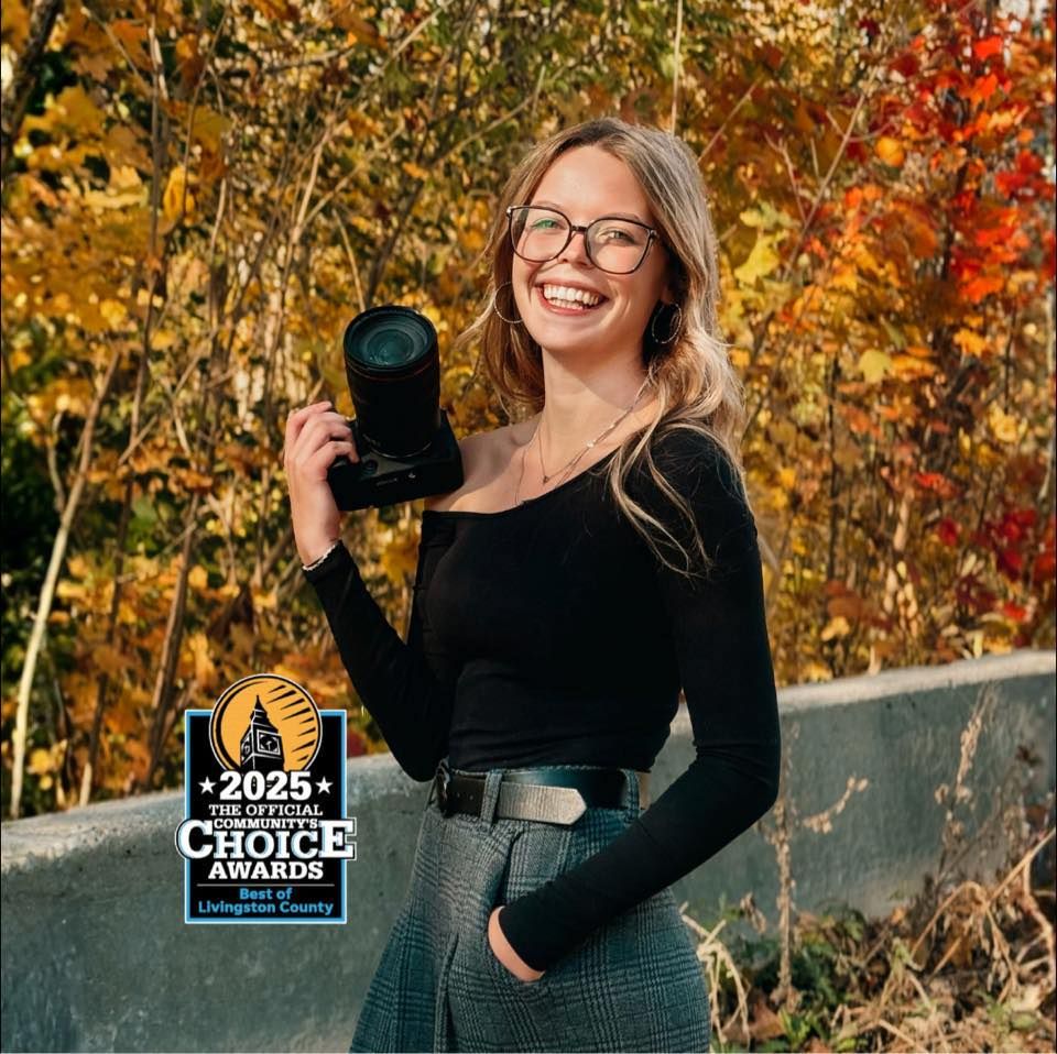 Professional photographer holding camera against vibrant autumn foliage backdrop with award finalist badge.