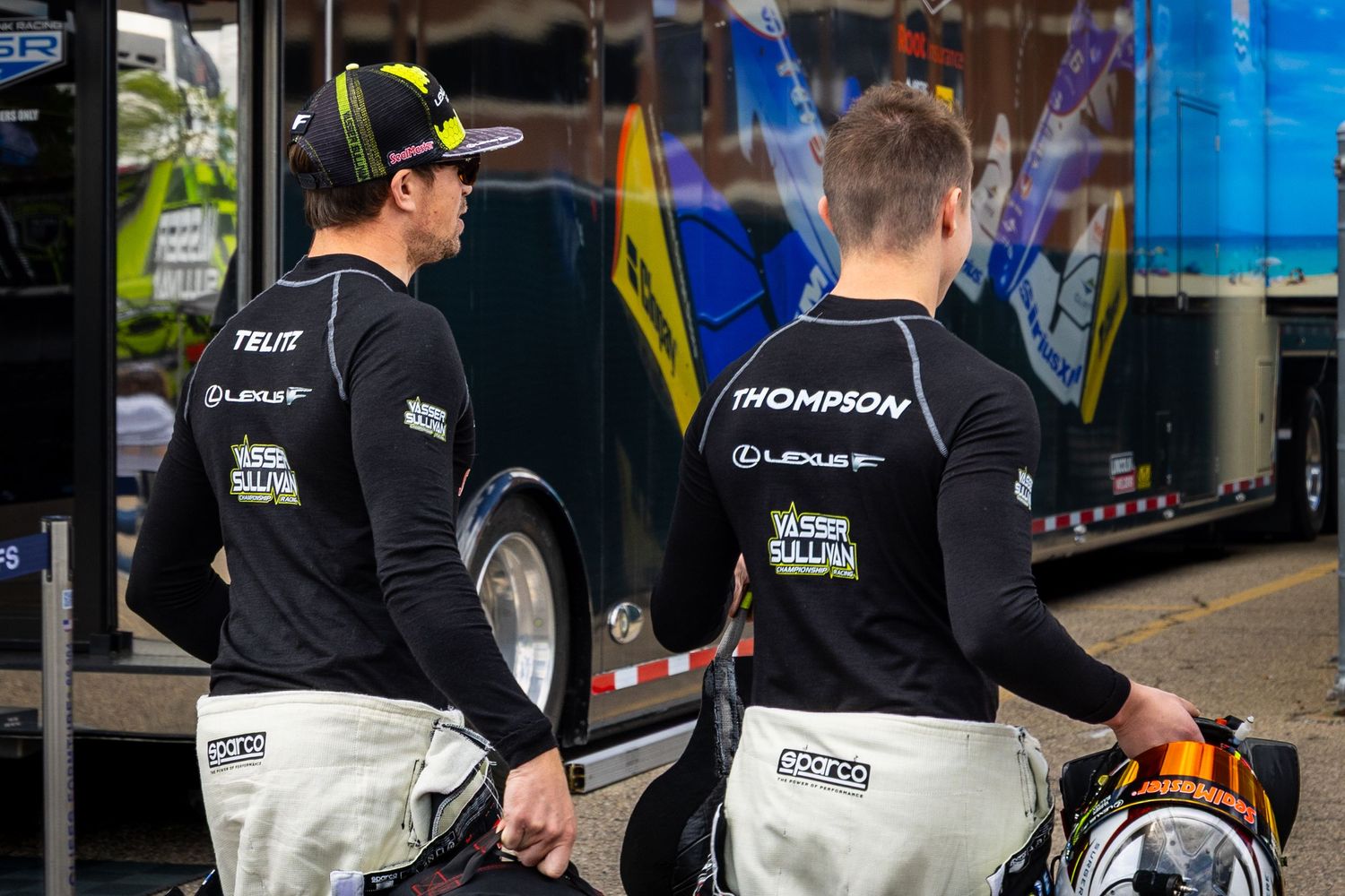 Racing team members in black uniforms working together in the pit lane.