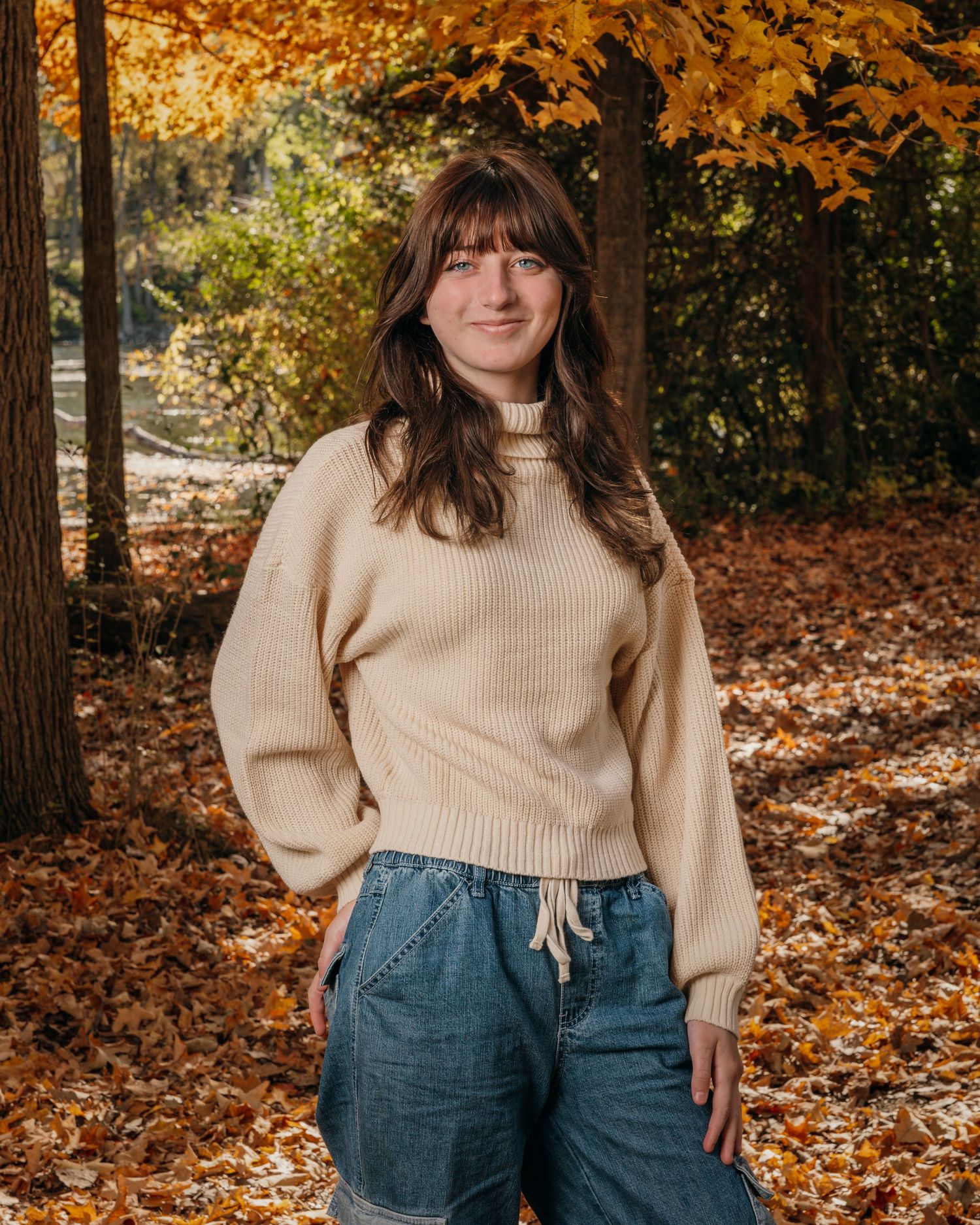 Autumn portrait with person in cream sweater against background of orange fall foliage.