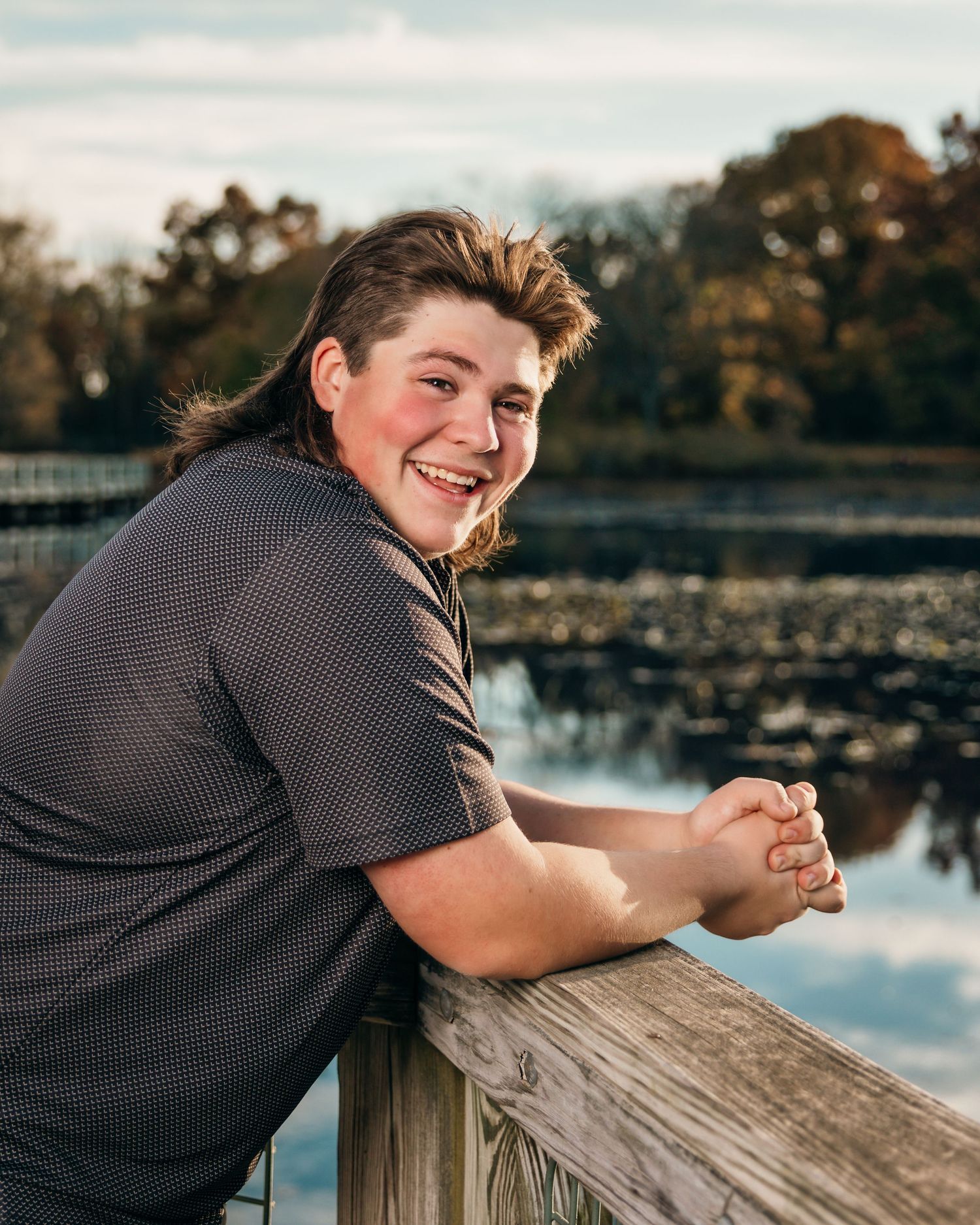 Person relaxing on wooden dock by lake during sunset photography session.