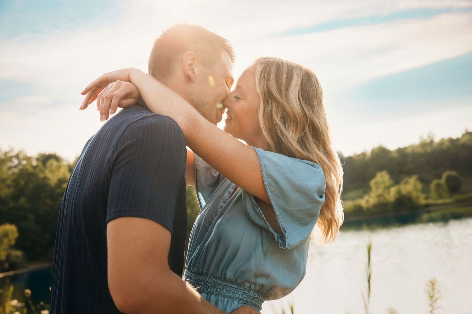 Romantic embrace by a lake during golden hour with beautiful natural lighting.