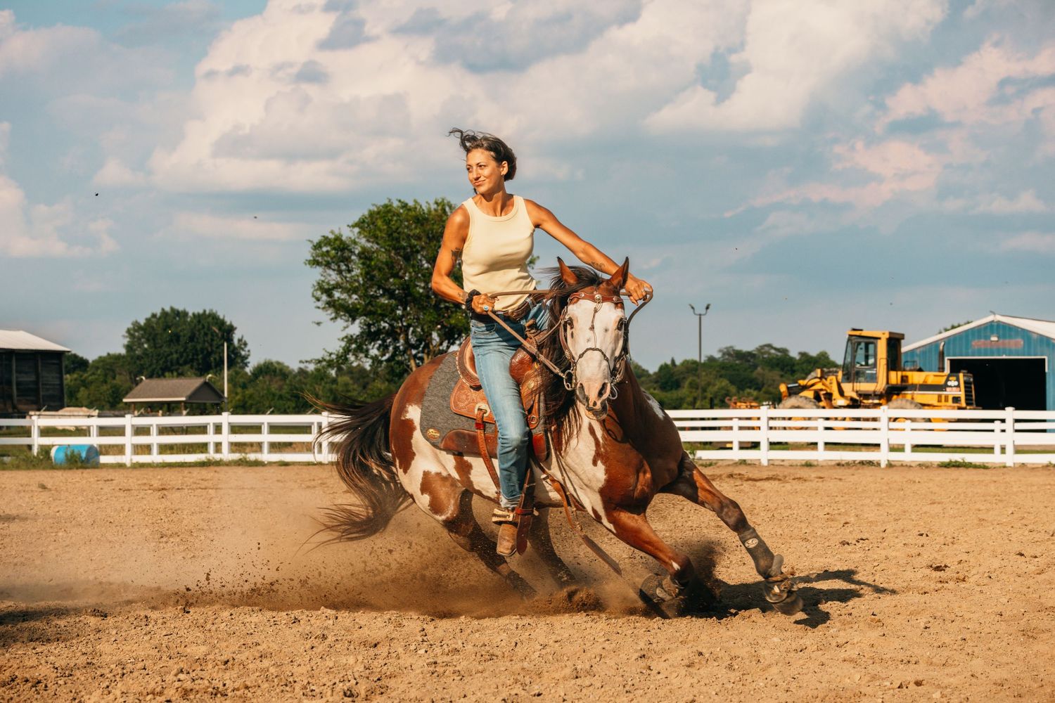 Riders navigate horses through a barrel racing course in an outdoor arena.