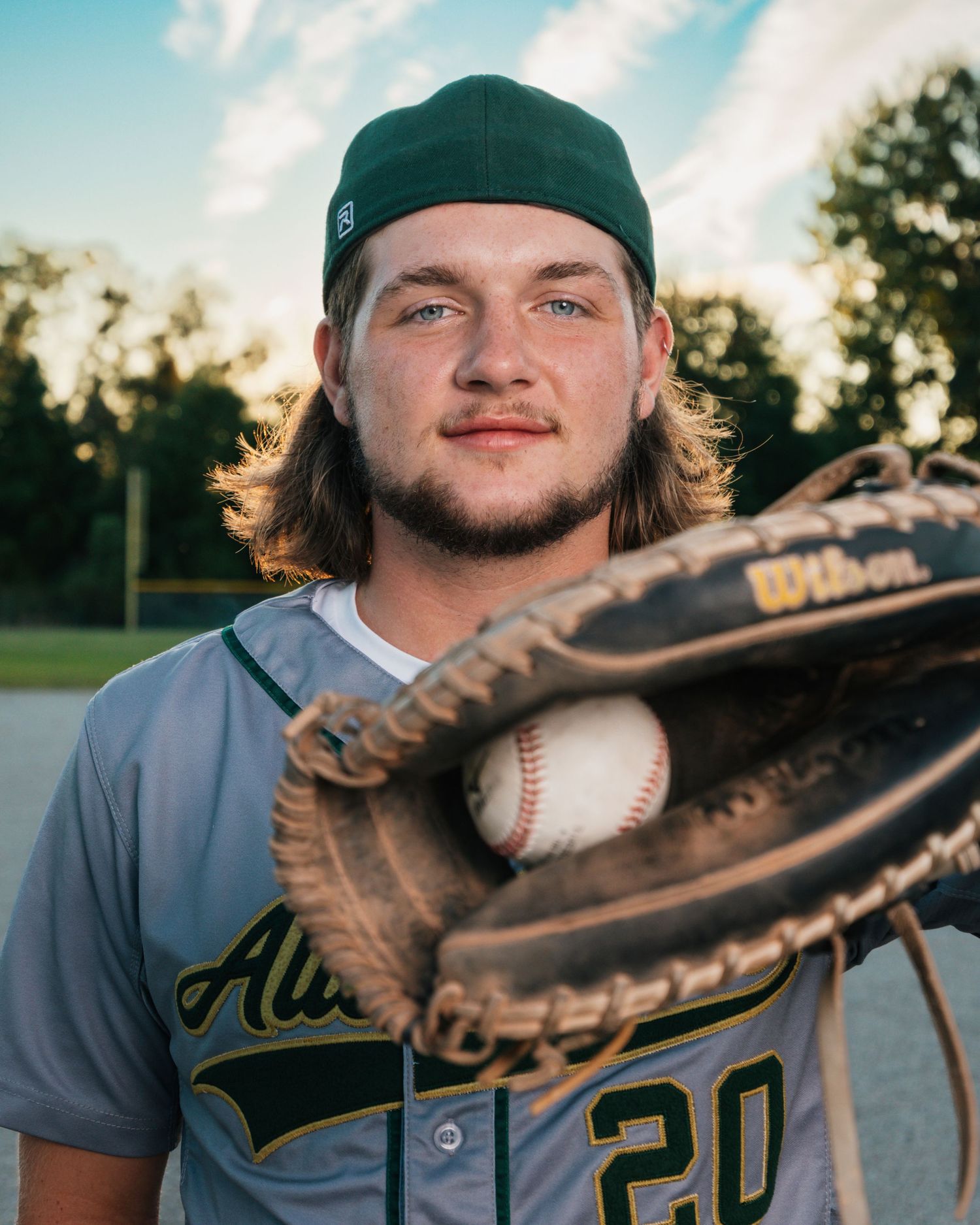 Baseball player in Allen Park uniform displays catching mitt during practice.