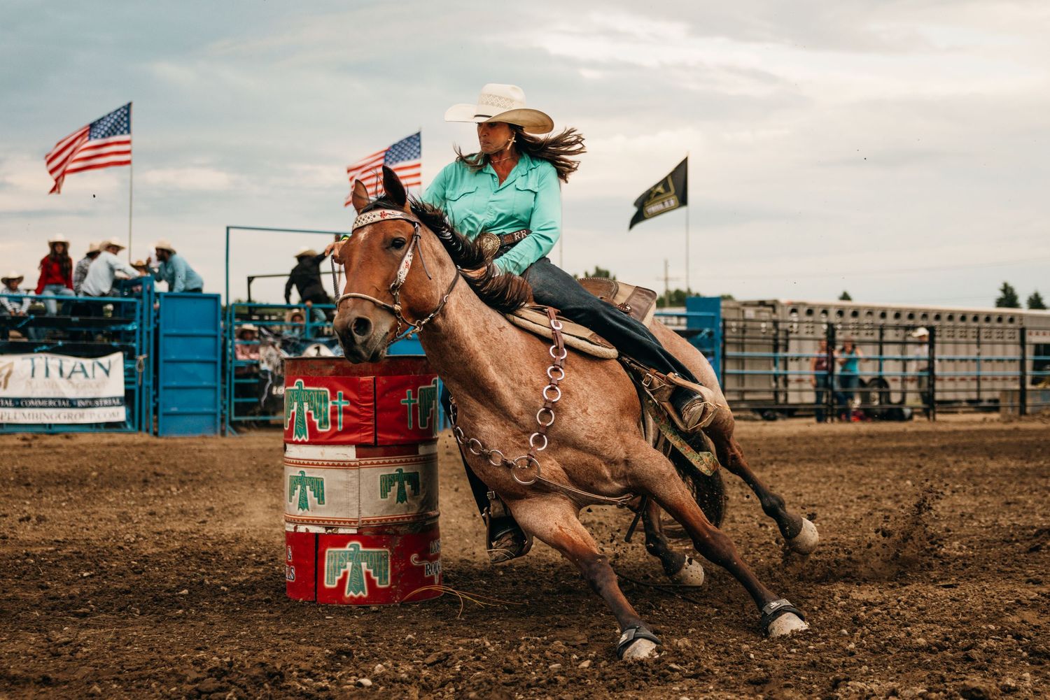 Rodeo action sequence showing barrel racing and American flag at a dusty arena during competition.