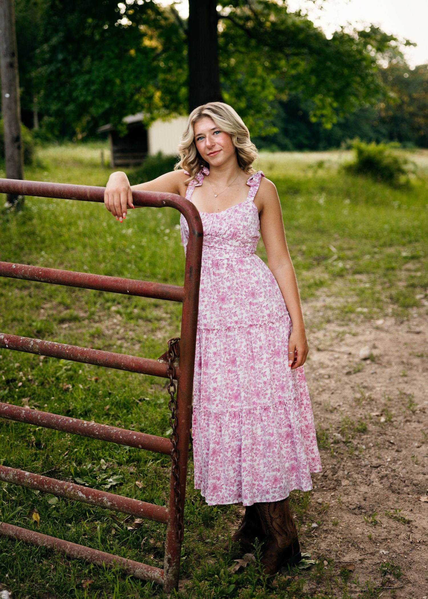 A pink floral sundress flows in the breeze near rustic metal railings.