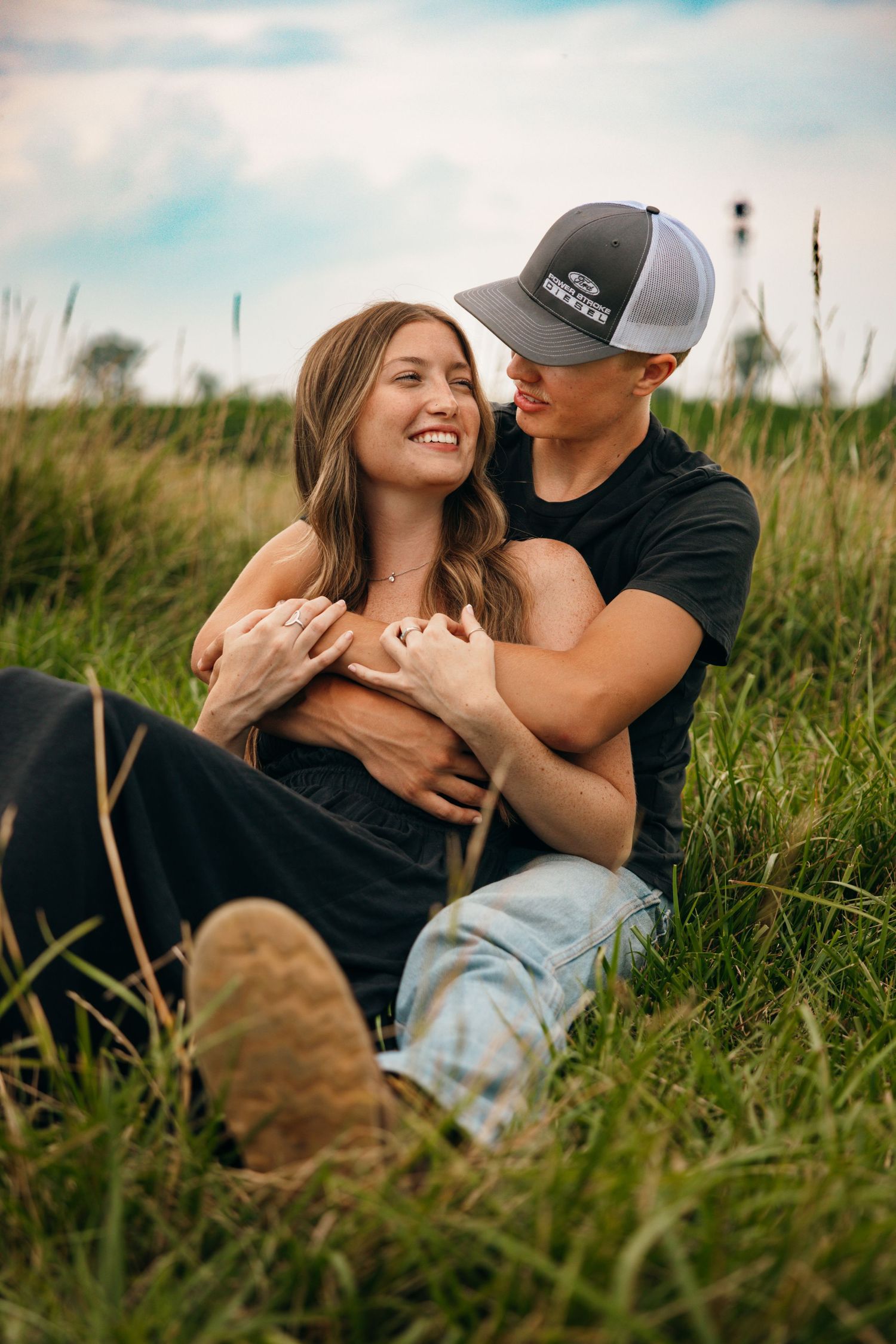 Couple relaxing together in tall grass field on sunny afternoon.