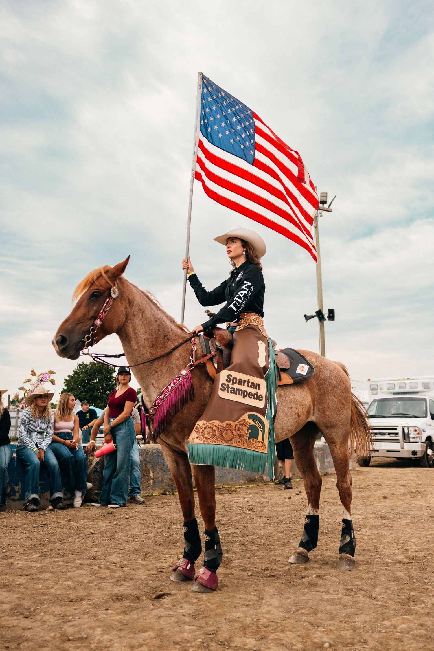 Horseback riders carrying American flags parade around the rodeo arena.