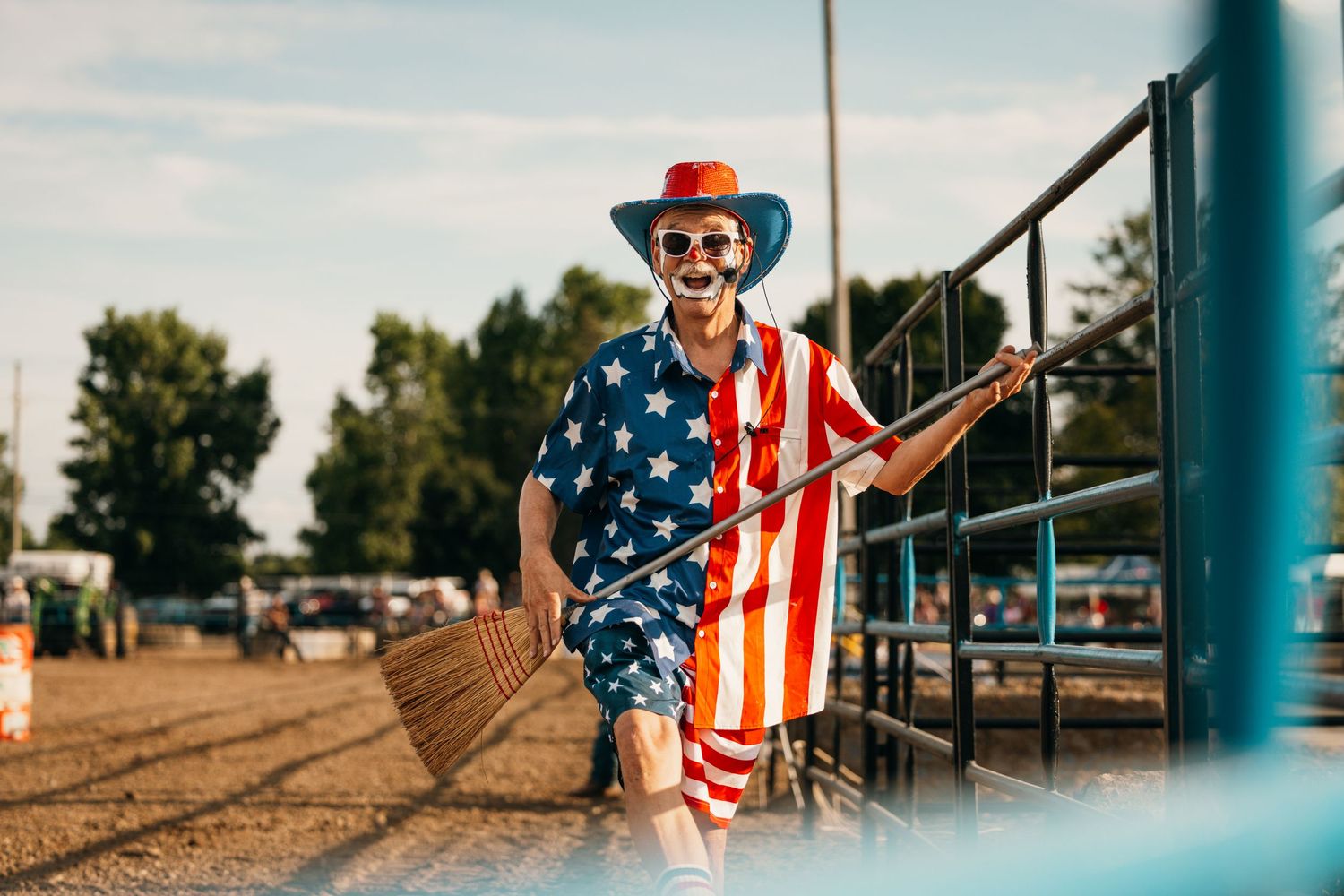 Rodeo scene with American flag decorations and spectators watching through metal railings.
