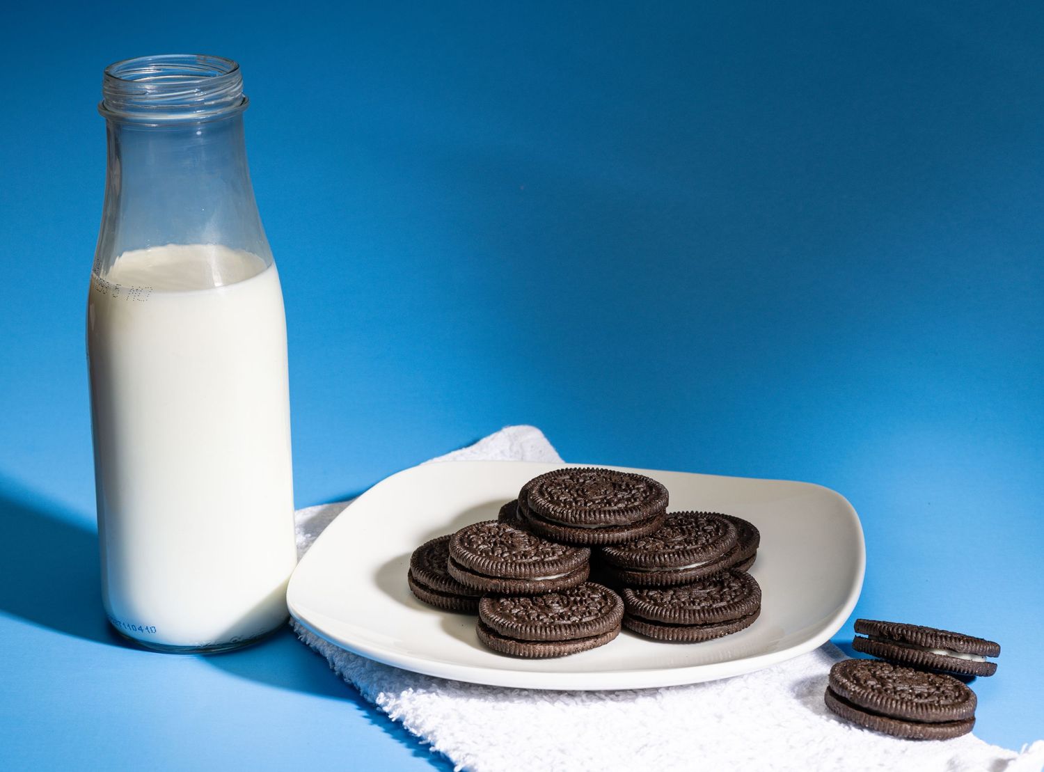 Classic chocolate sandwich cookies arranged on white plate with glass of milk.