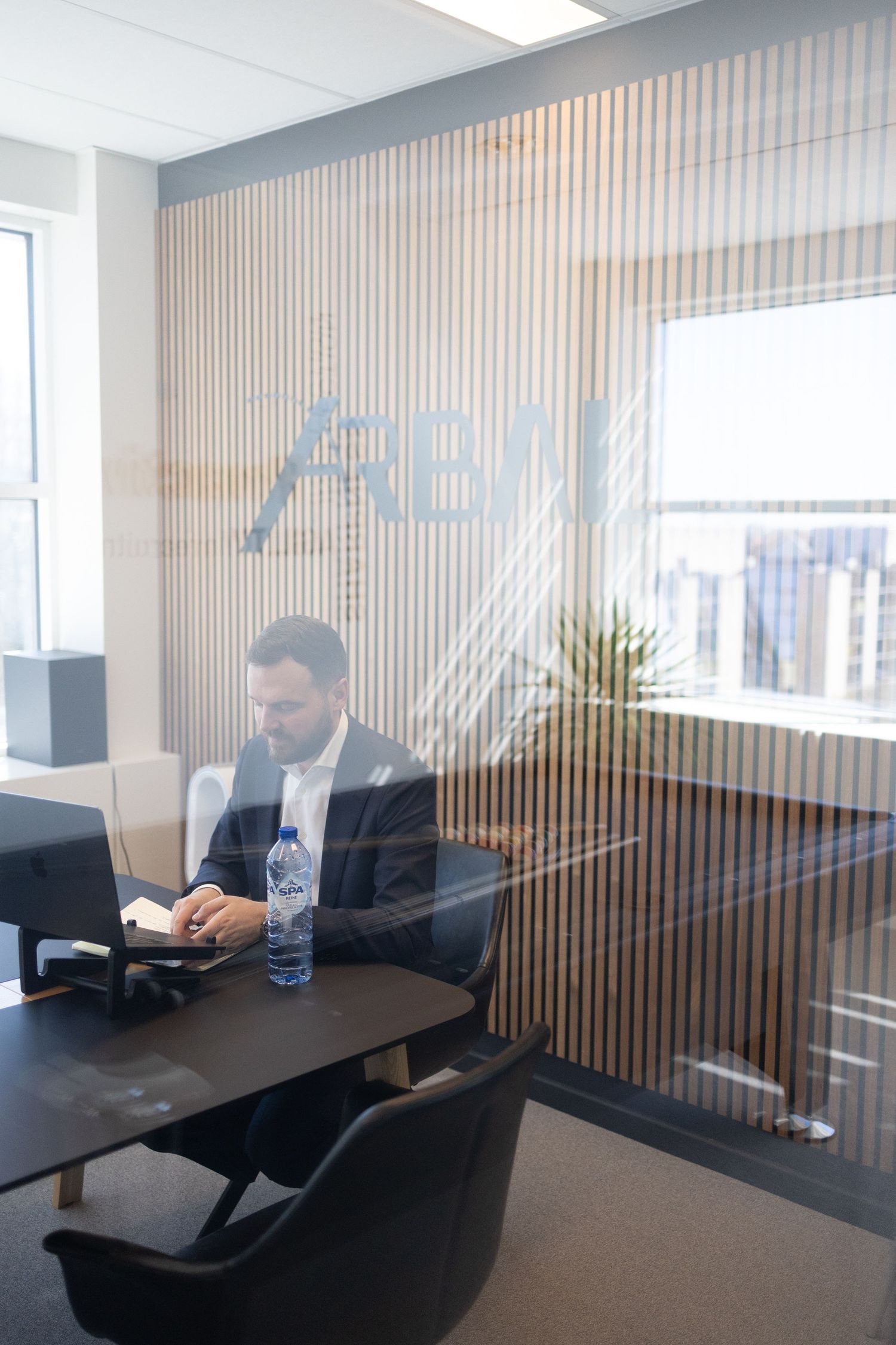 Portrait professionnel en bureau vitré – photographe corporate Bruxelles, dirigeant au travail, branding entreprise, environnement business.