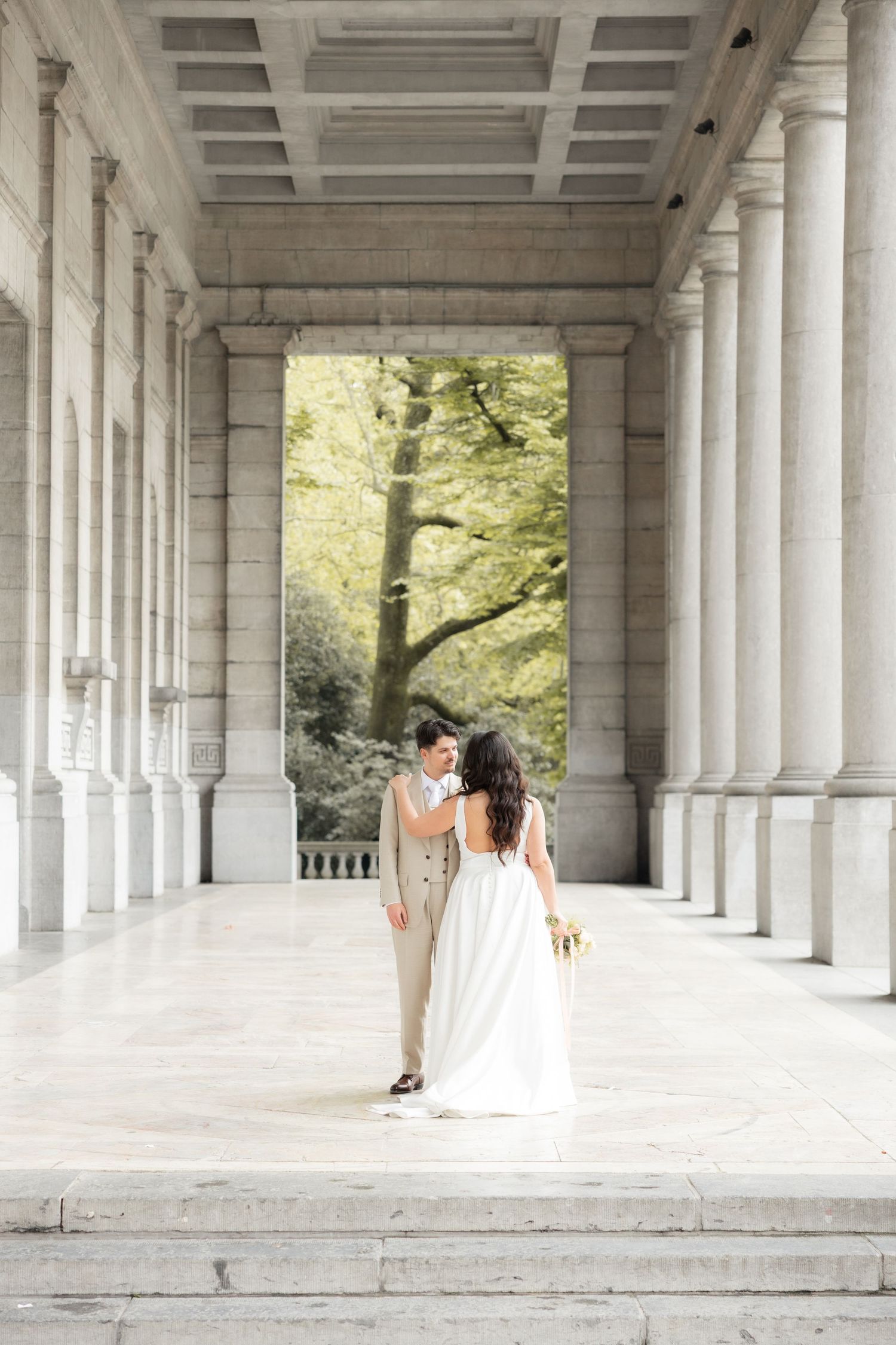 Couple mariés sous colonnades, photo mariage civil Belgique, photographe mariage Bruxelles, pose élégante, architecture et lumière naturelle