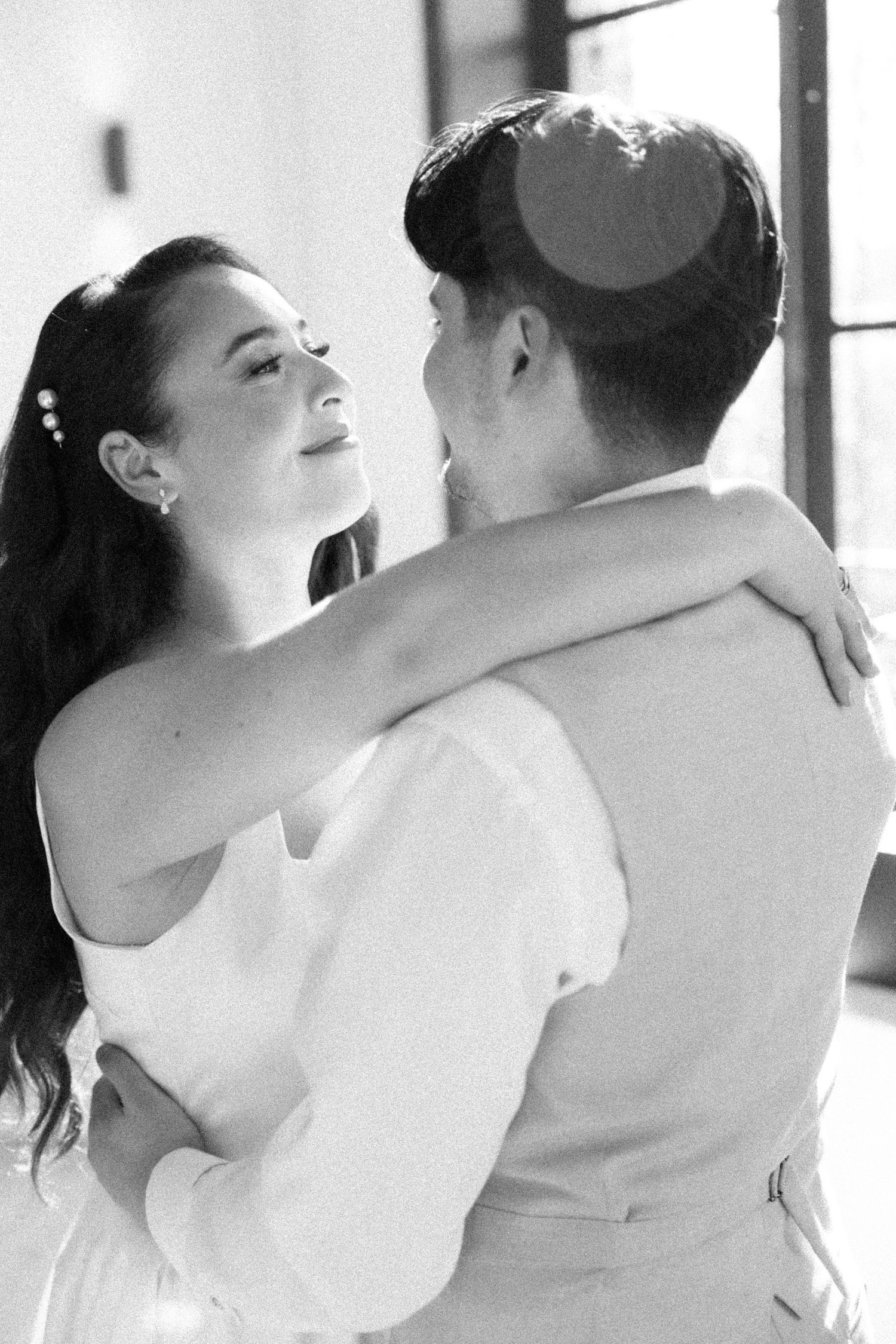 Couple enlacé près fenêtre, photo mariage civil Belgique, photographe mariage Bruxelles, instant tendre, lumière naturelle et spontanéité