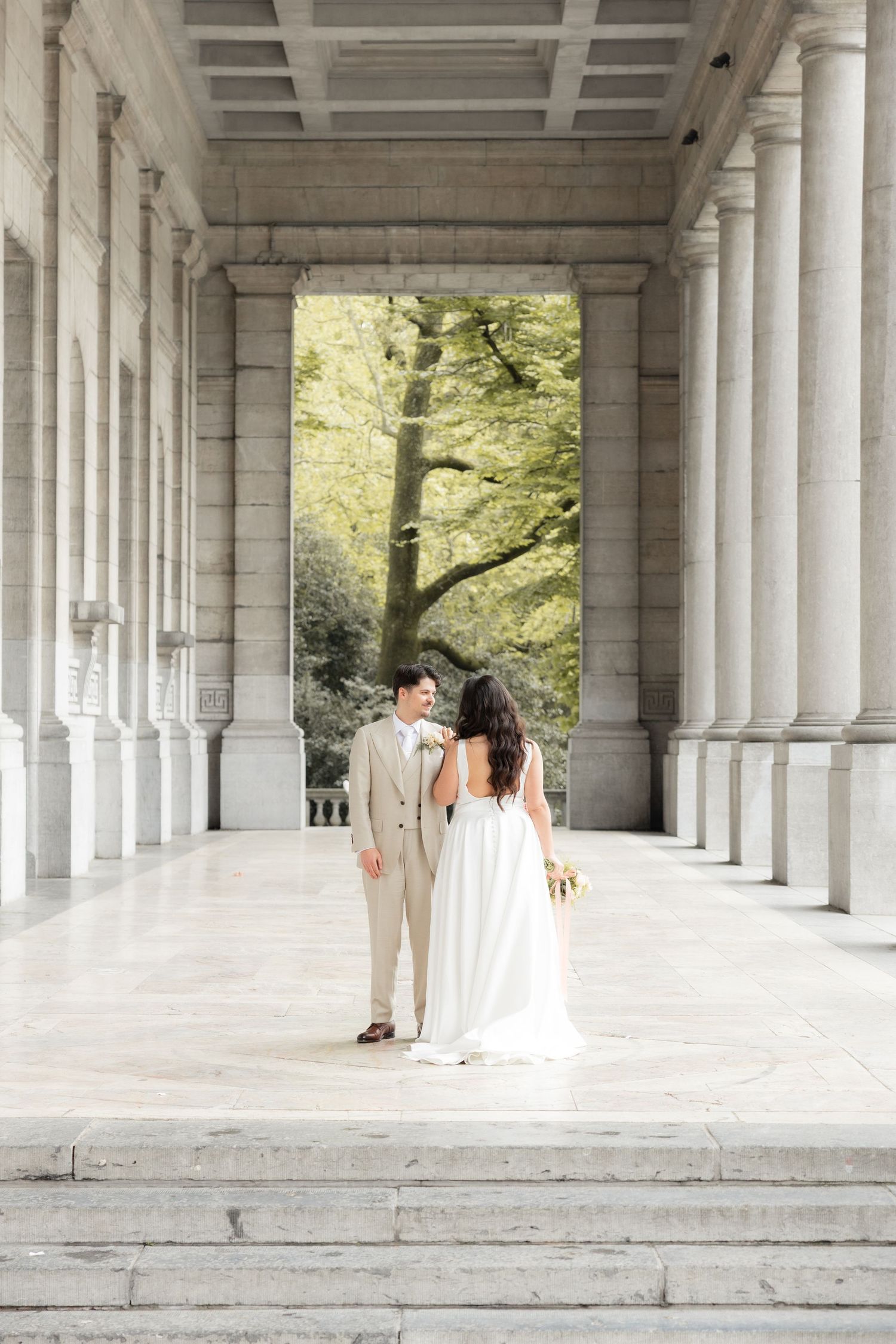 Couple de mariés lors d’une séance photo de mariage civil à Bruxelles, dans un lieu architectural élégant, reportage naturel.