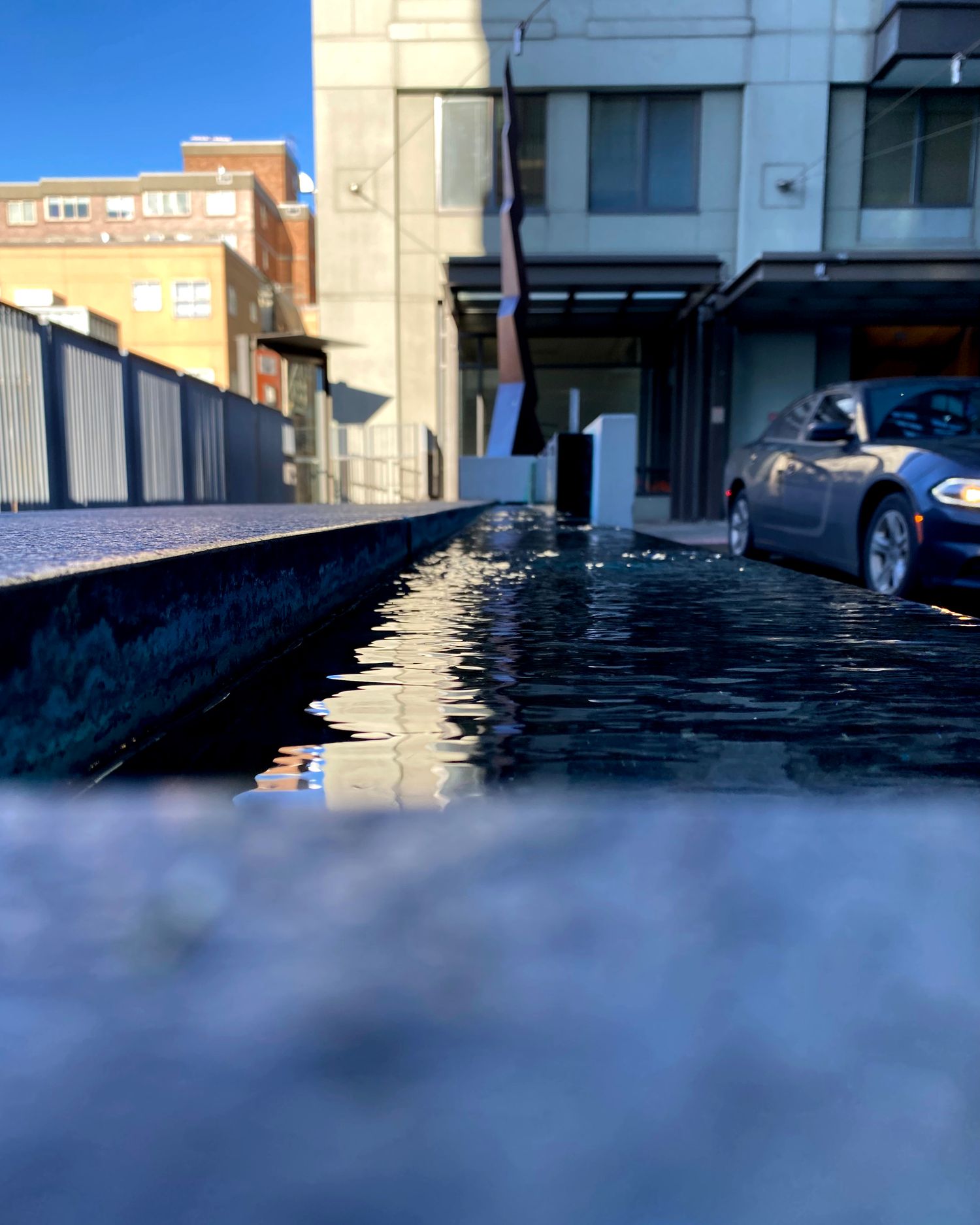 Abstract reflection of sunlight on wet surface creating mirror-like effect in urban setting.