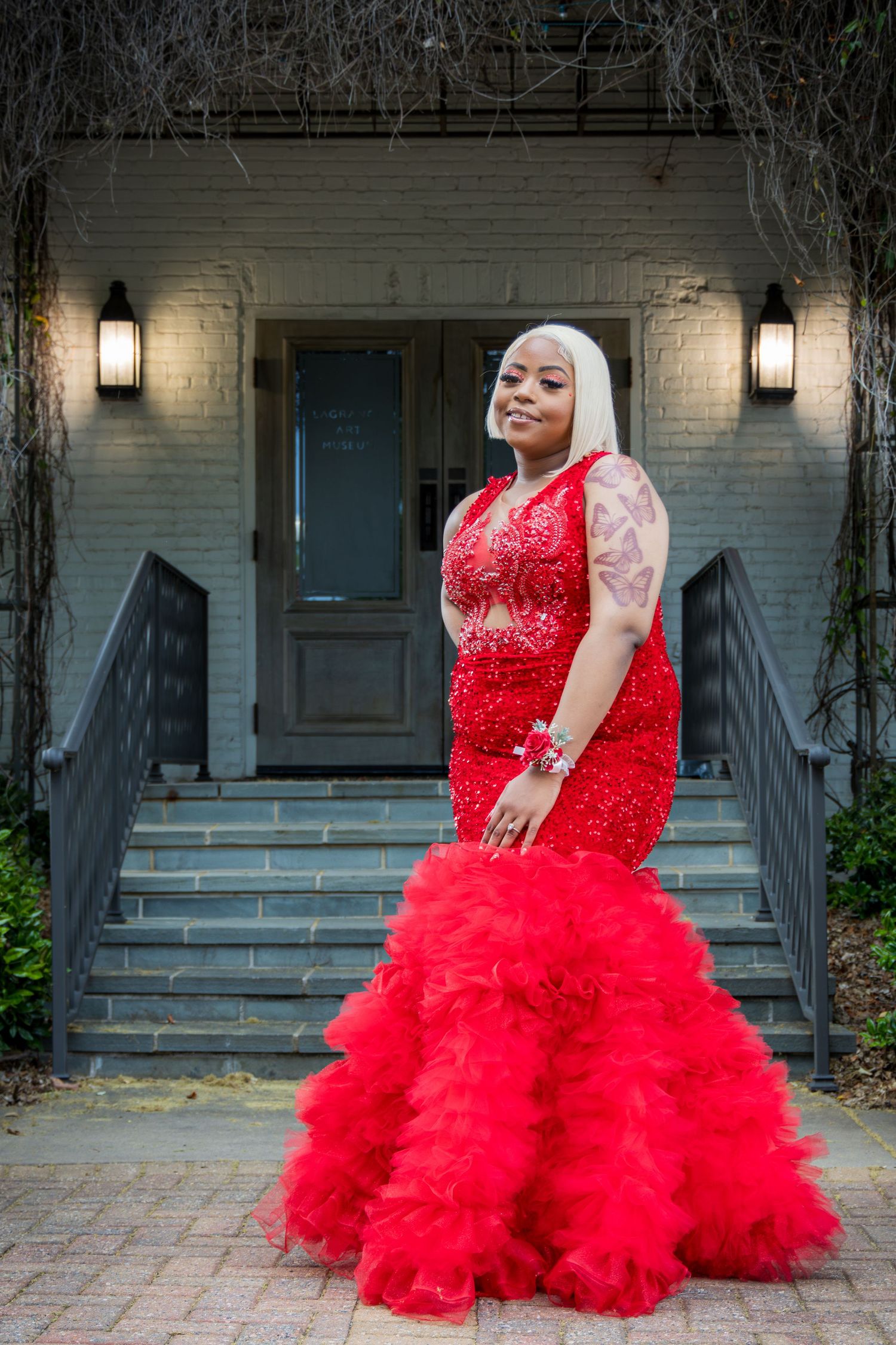 A stunning red tulle ball gown with lace bodice photographed against a rustic porch backdrop.