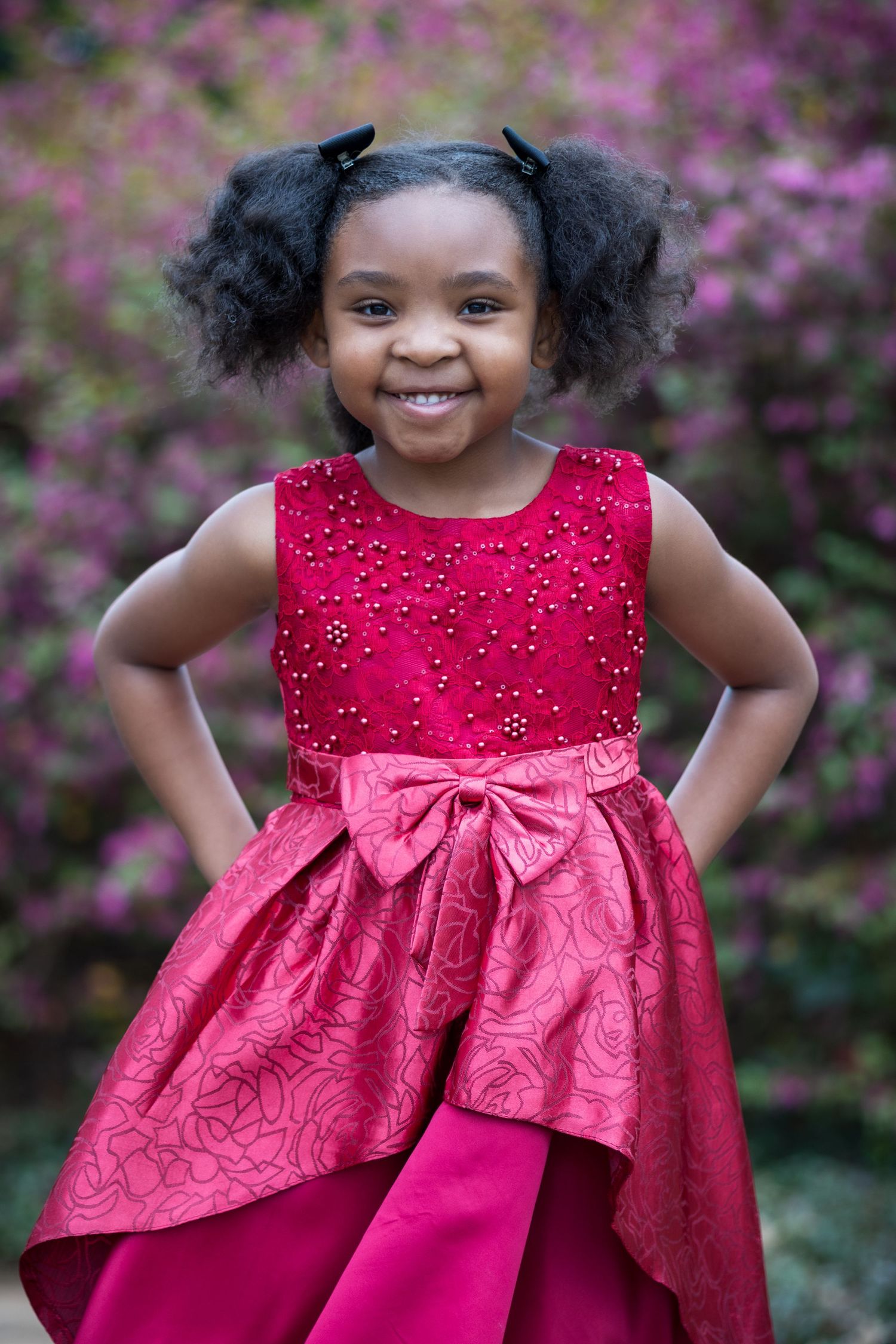 A red formal dress with sequins and bow details photographed outdoors.
