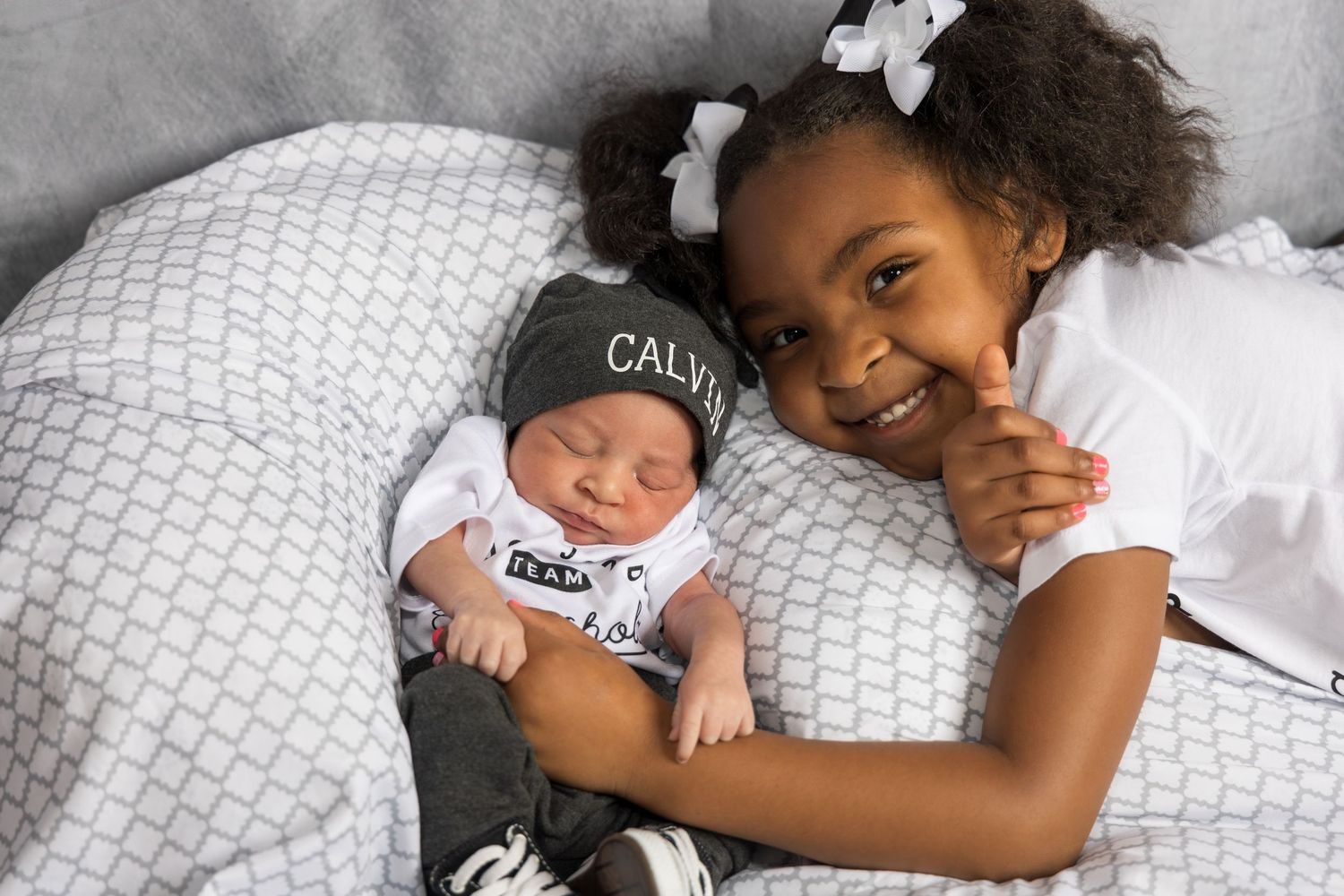 Black and white newborn lifestyle photography session on white bedding.