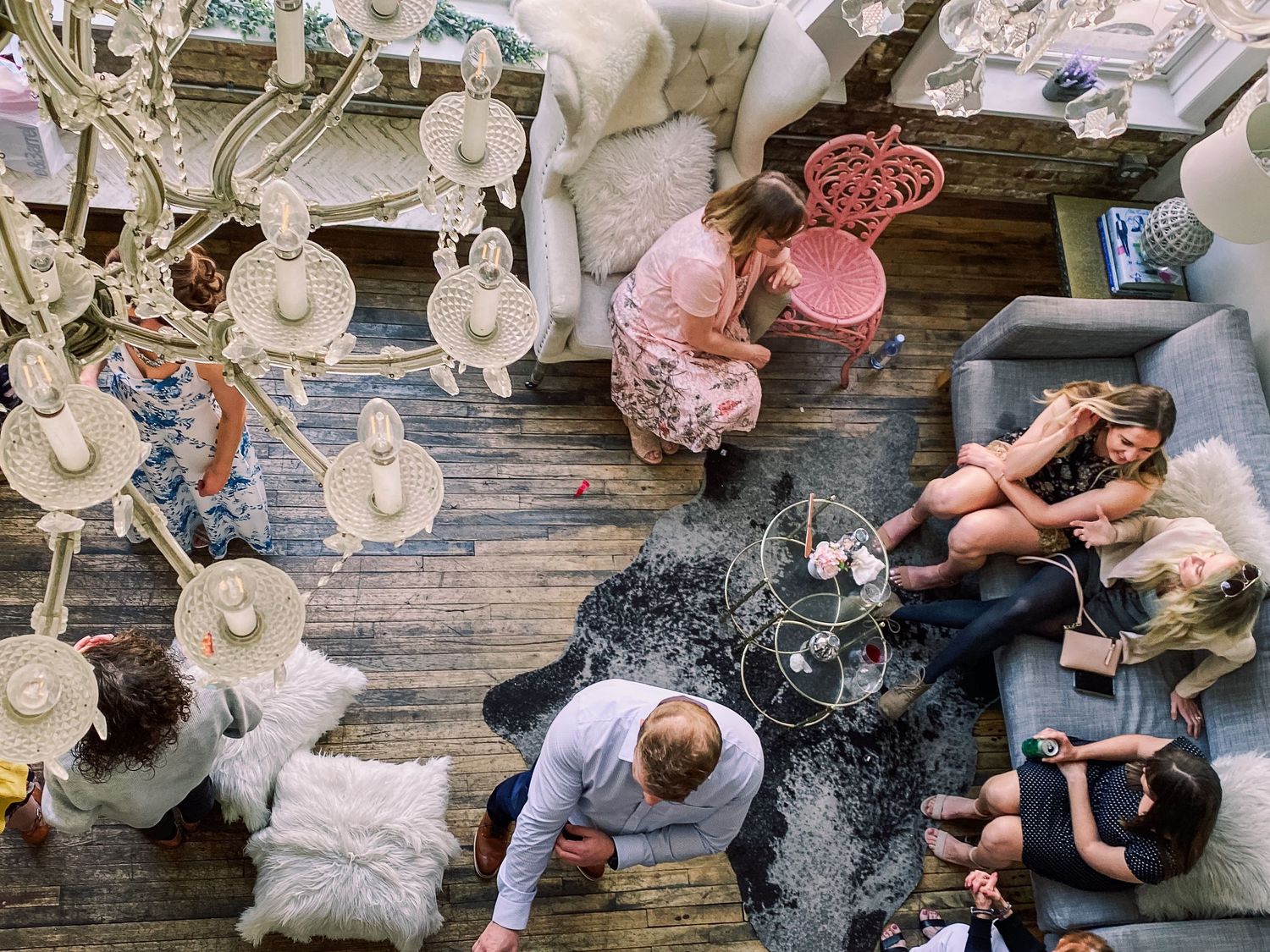 Aerial view of group of people relaxing in stylishly decorated living room with chandelier.