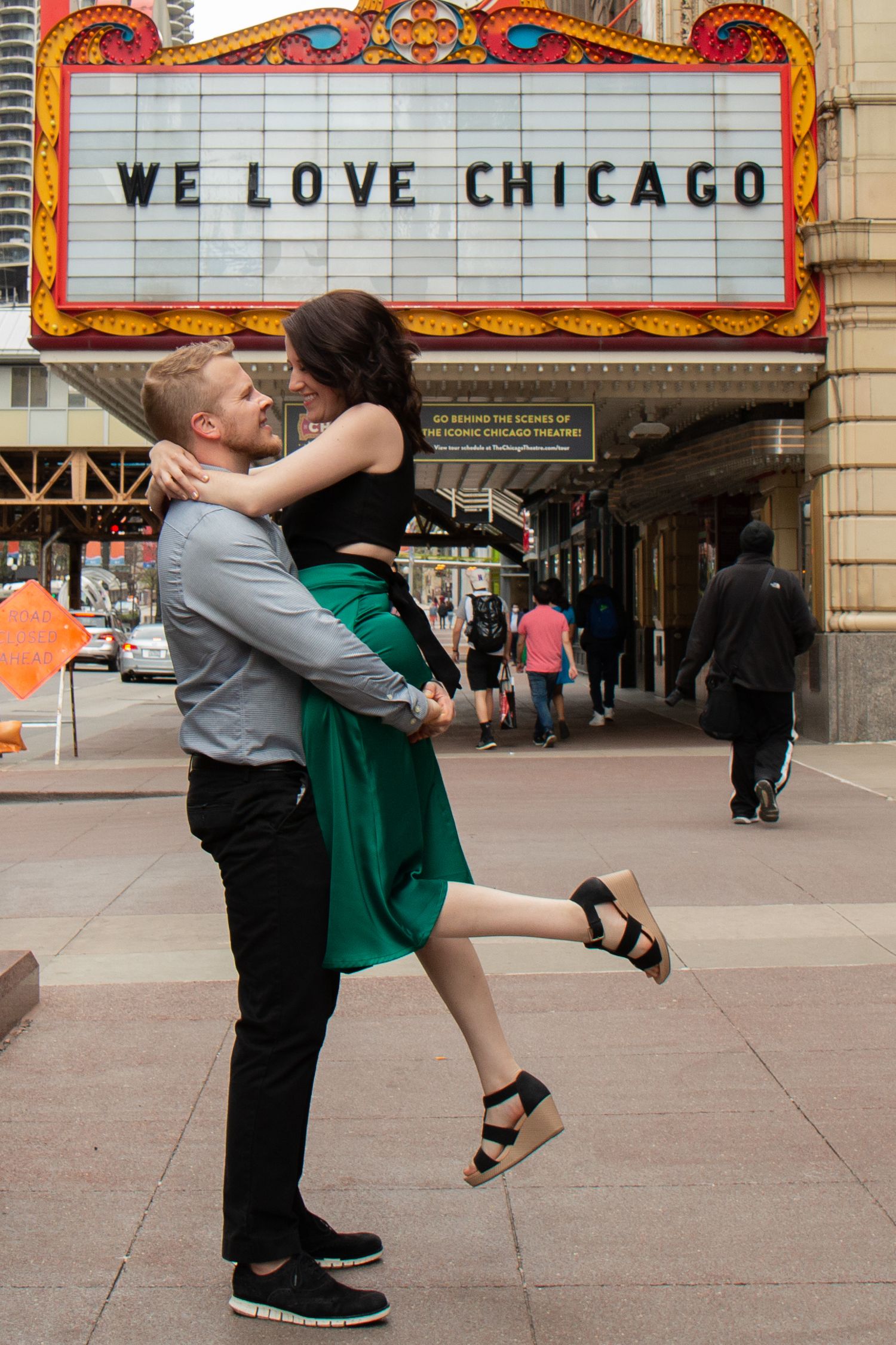 Couple embracing and dancing in front of the iconic Chicago Theatre marquee reading We Love Chicago.