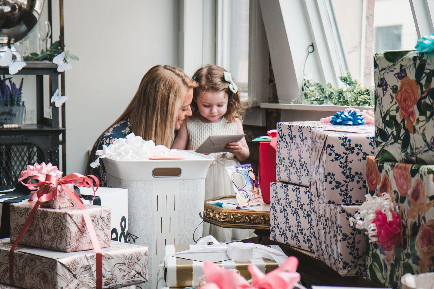 Woman and little girl with flower crown reading a card surrounded by wrapped gifts at a bridal shower.