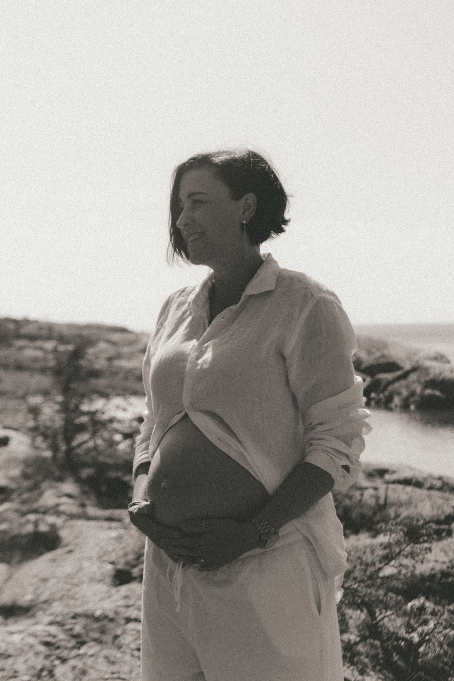 Black and white photos capture intimate moments between a couple on a rocky shoreline.