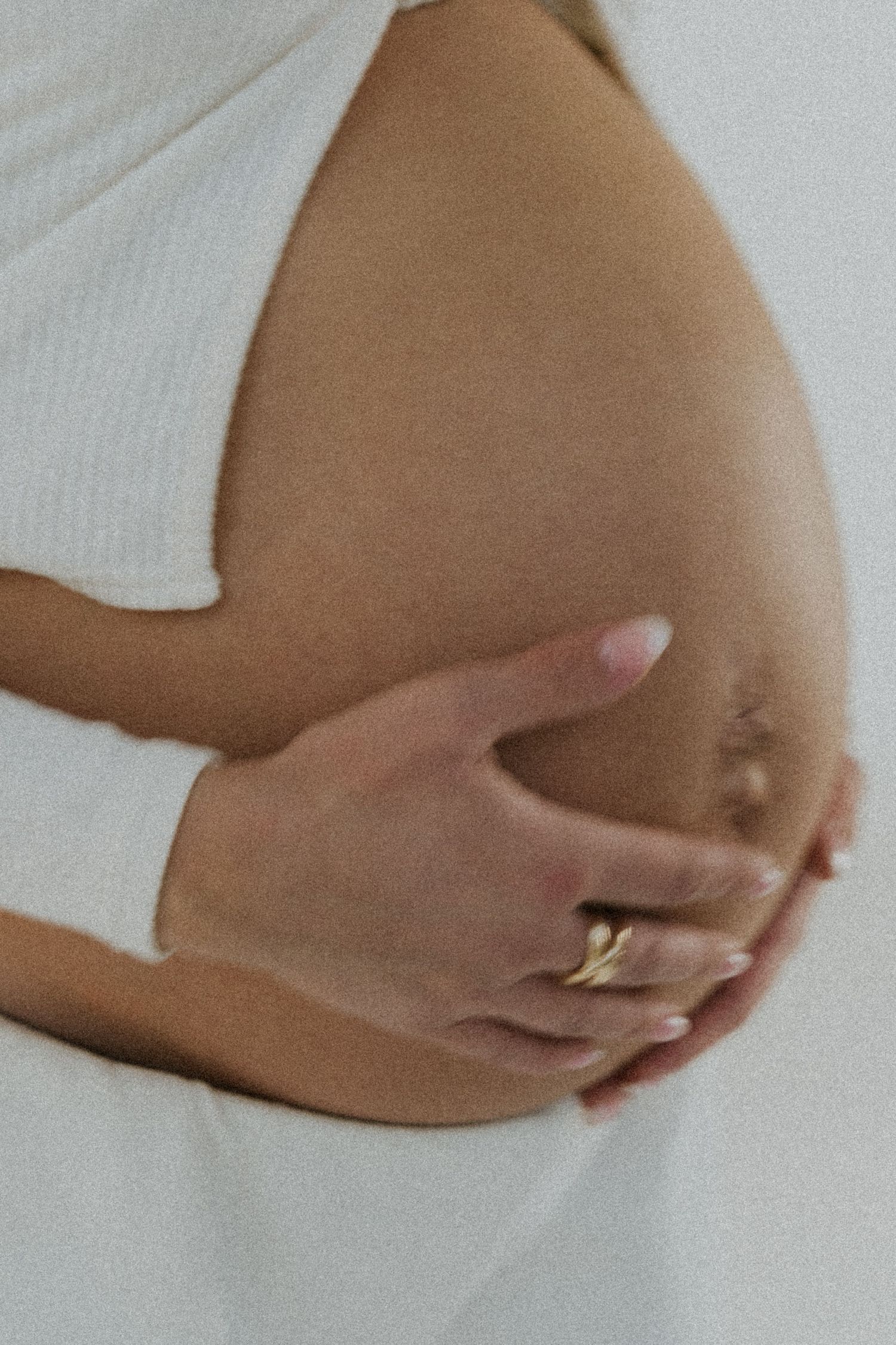 Close-up shots of a pregnant belly with hands gently cradling the bump against a light background.