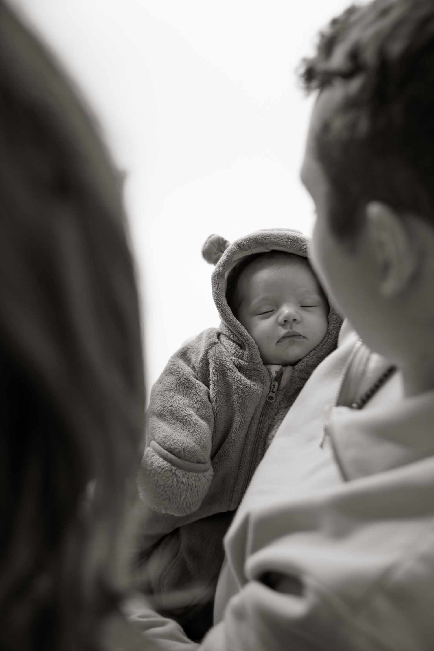 Black and white series of parents gazing at their sleeping newborn in gentle lighting.