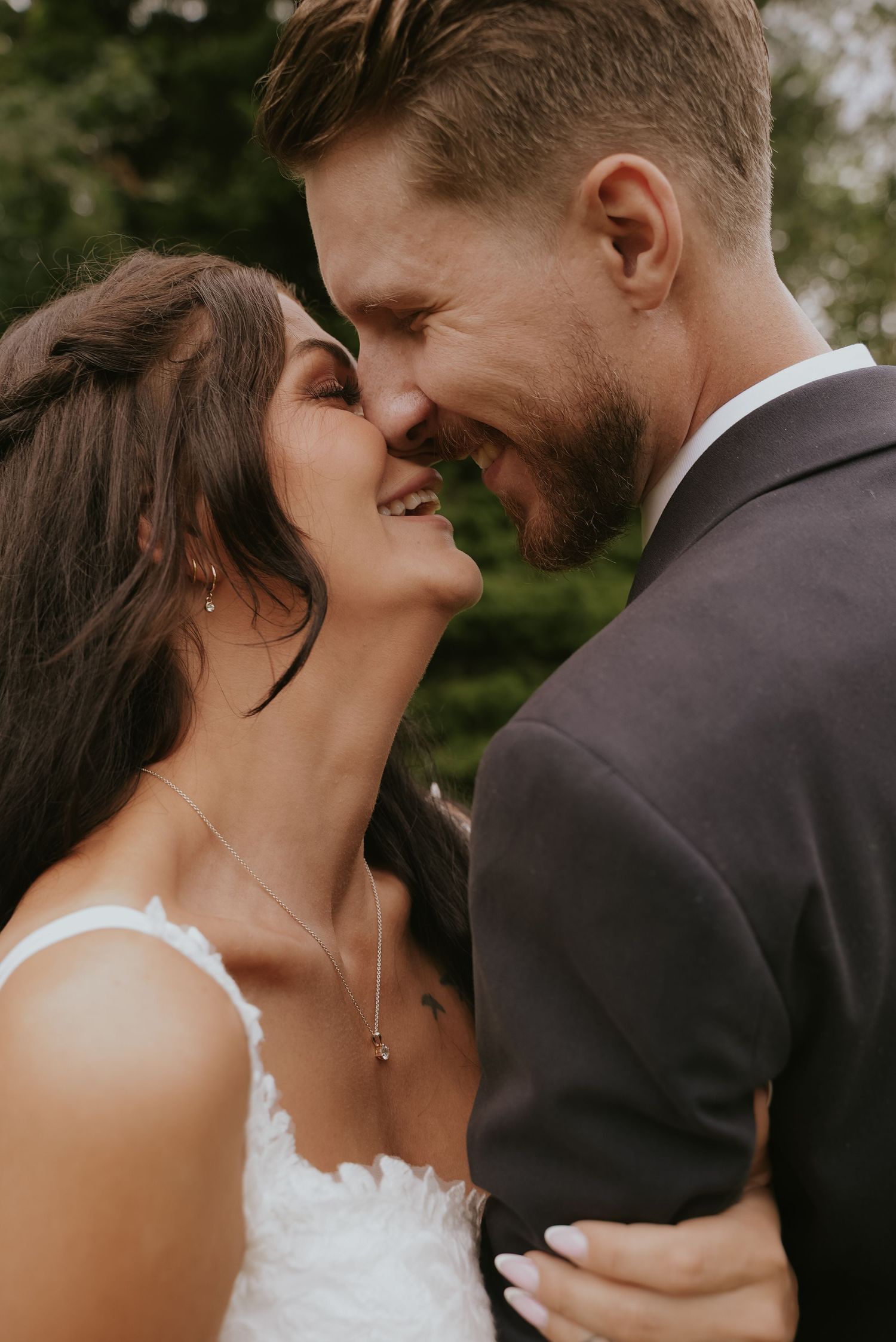 Romantic wedding couple embraces in intimate close-up shots showing tender moments against natural outdoor backdrop.