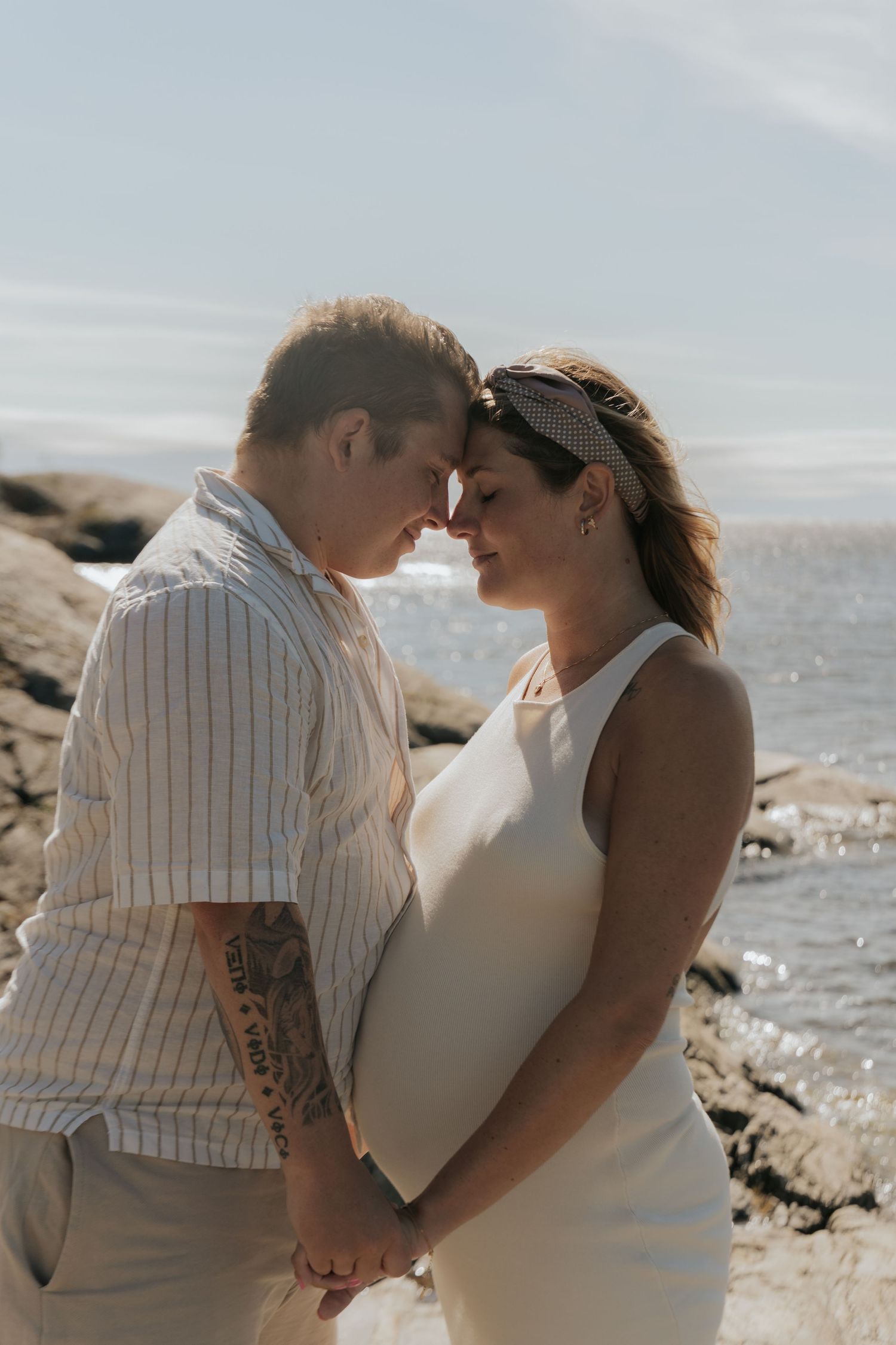 Romantic beach maternity photos with couple embracing by the ocean.