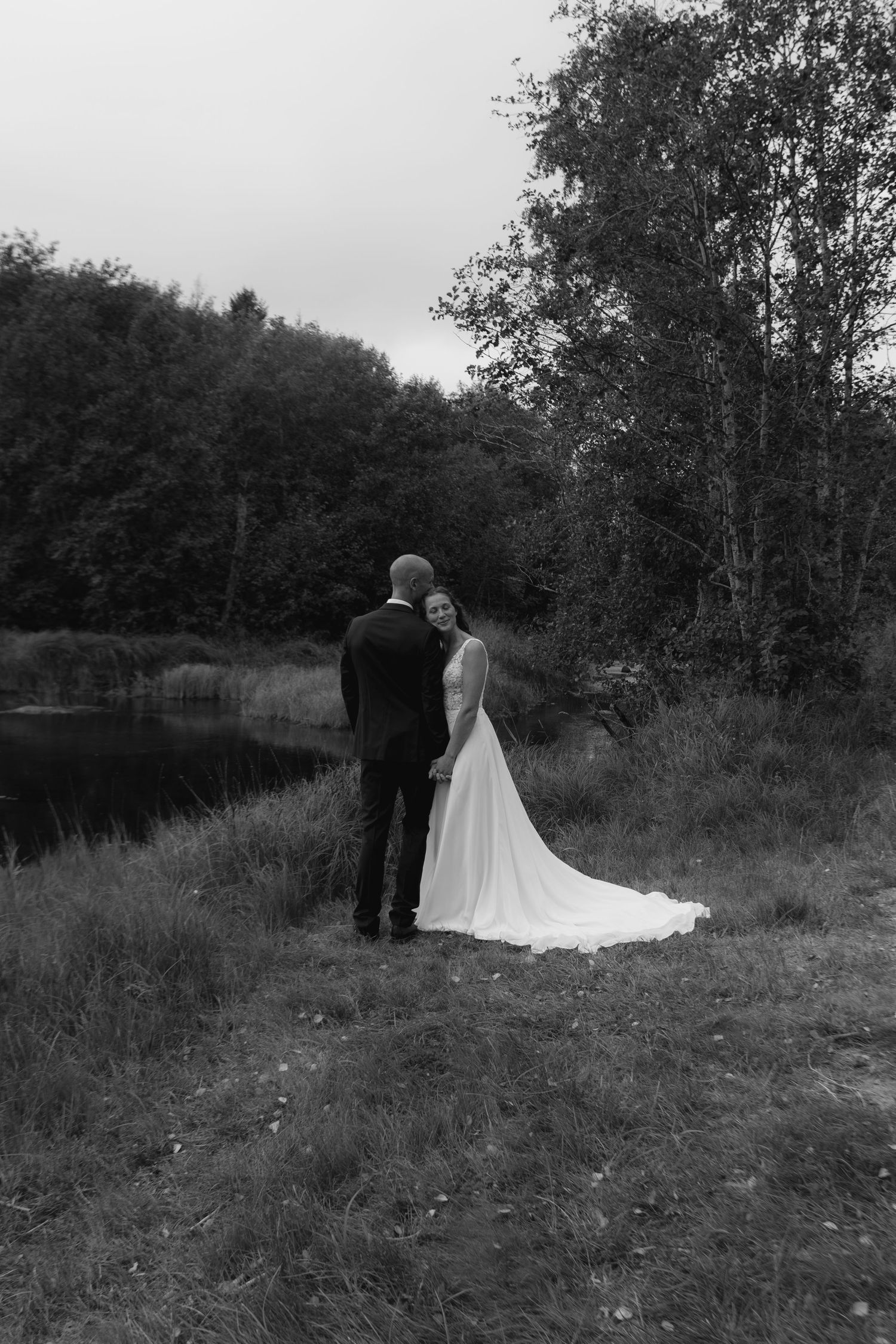 A romantic black and white wedding photo series showing a couple in an outdoor field setting.