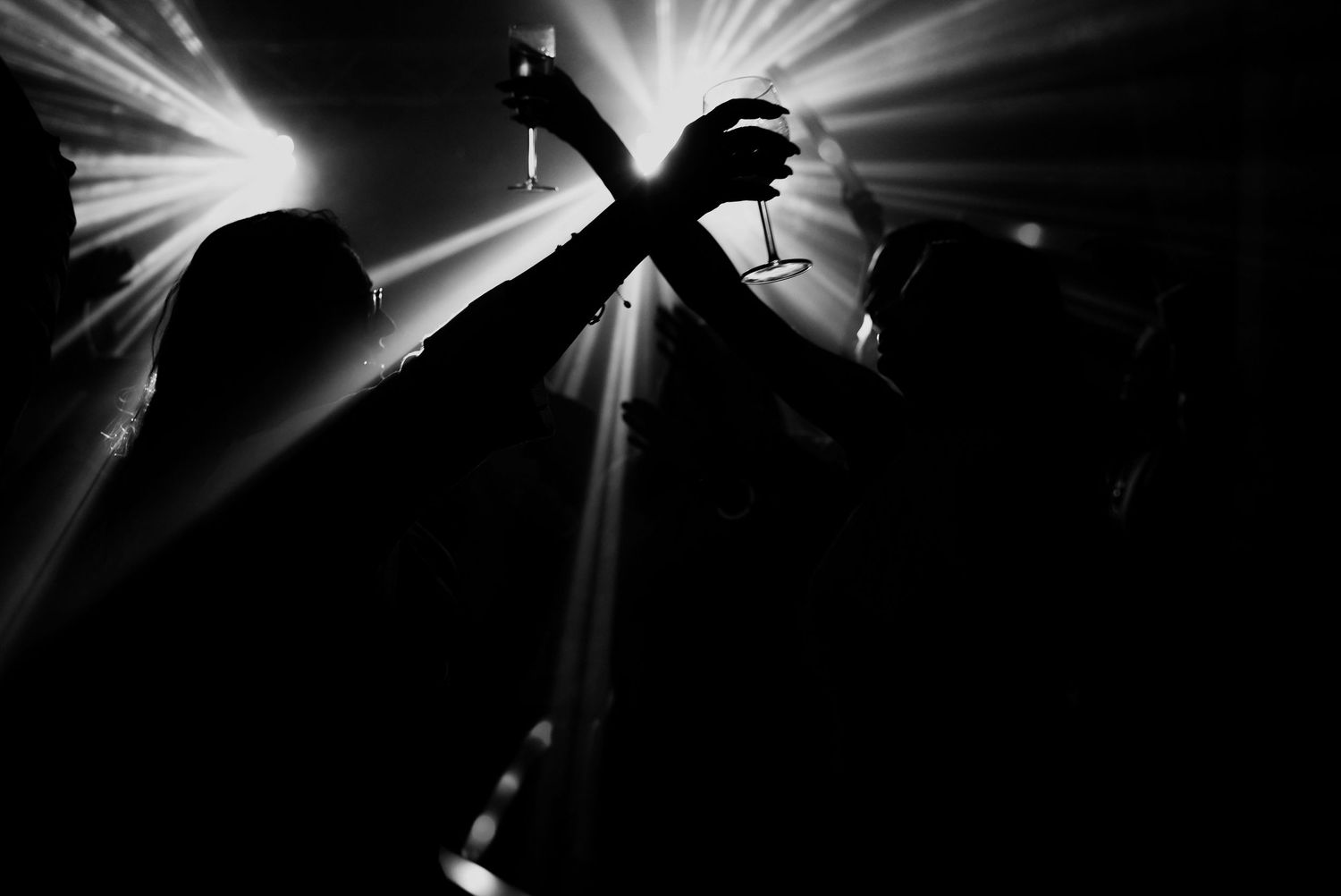 Bright beams of white light burst through darkness creating dramatic rays and shadows in a monochrome composition.