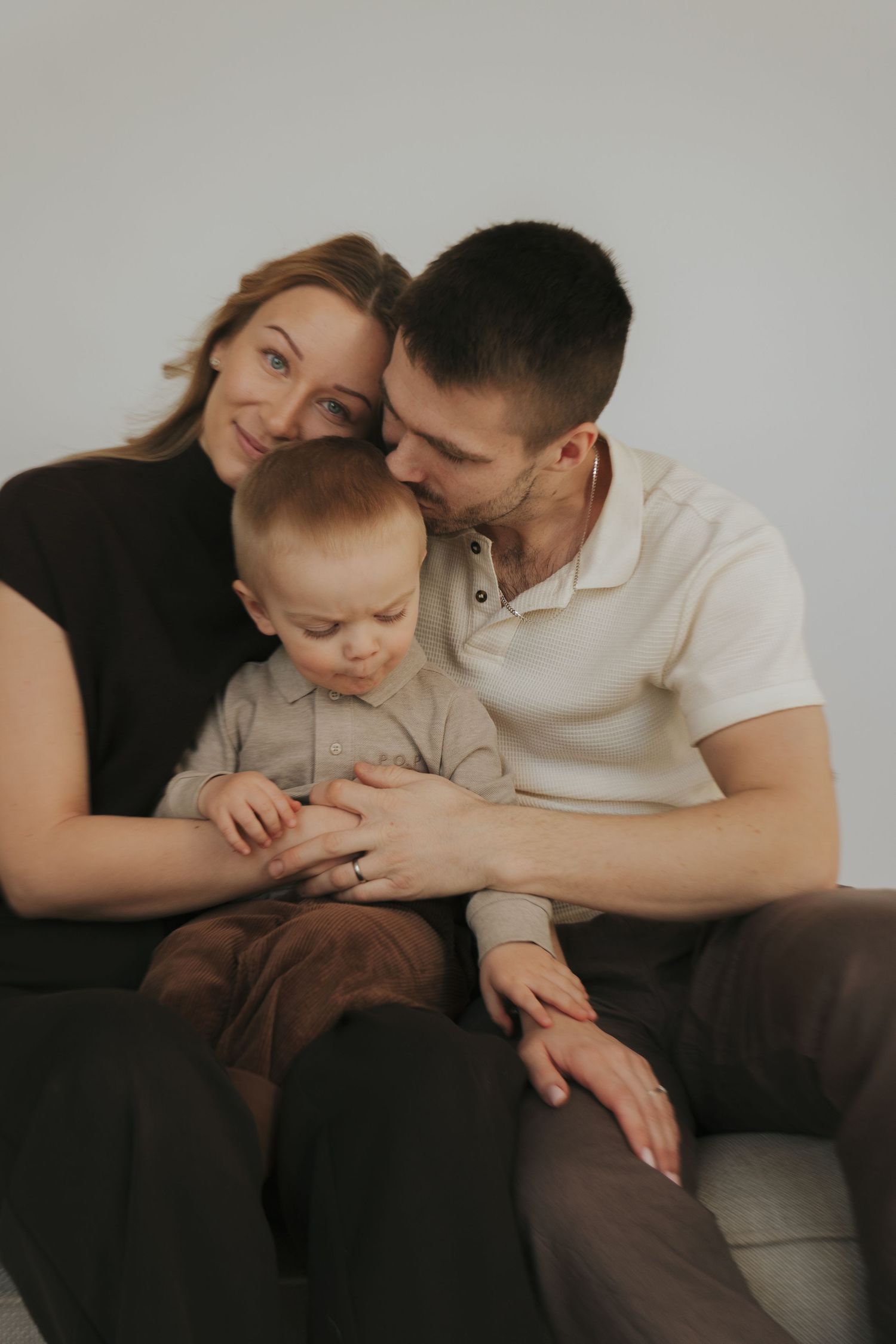 A family shares an intimate moment together on a couch in muted, moody lighting.