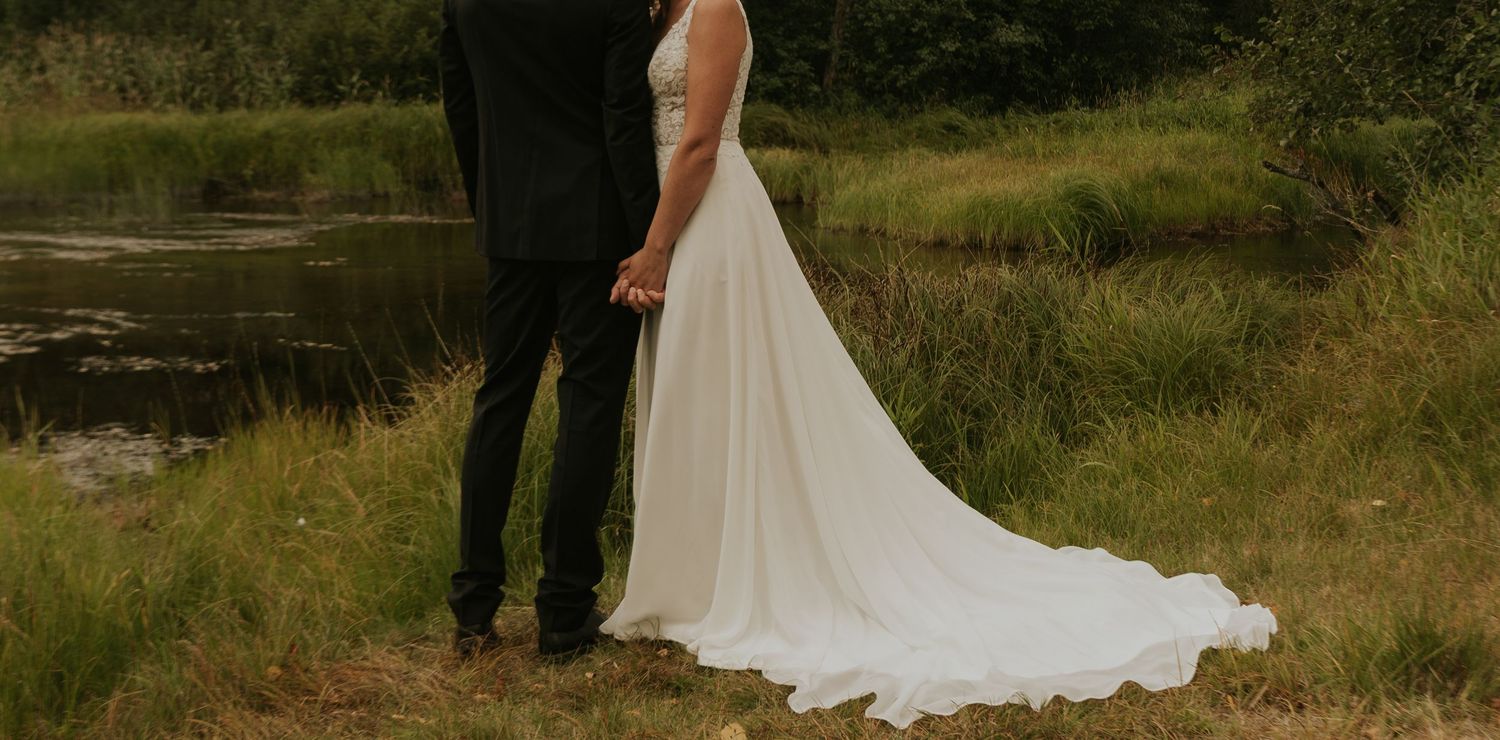 Wedding couple embracing on a scenic mountain overlook with flowing white dress.