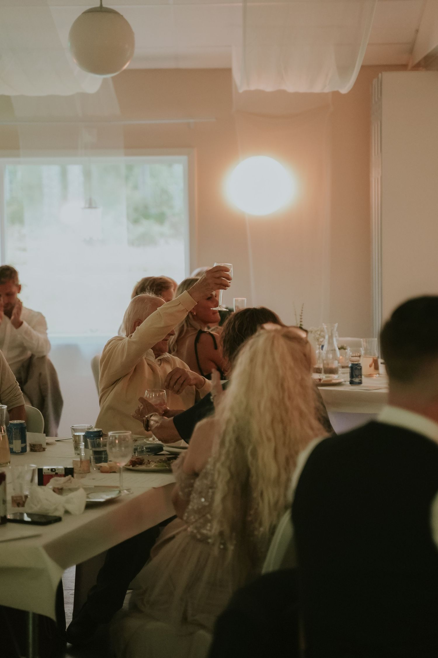 A sequence of four wedding reception photos showing guests mingling and dining in a bright indoor venue.