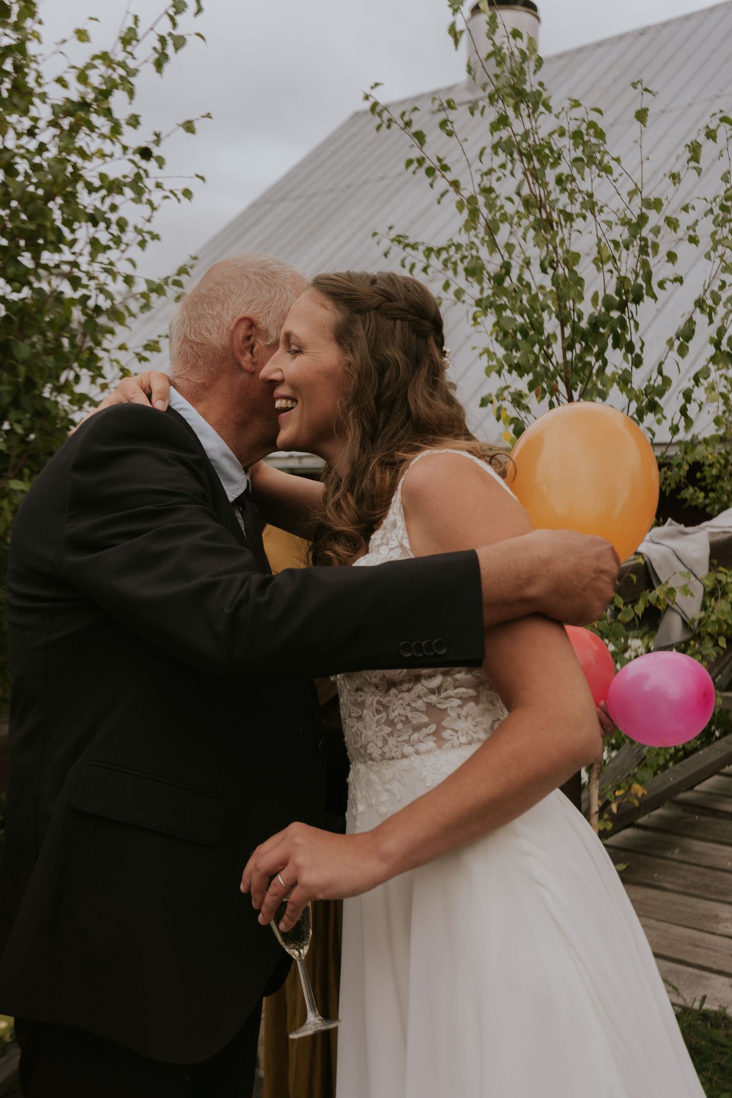 A romantic wedding moment with colorful balloons against a rustic barn backdrop.